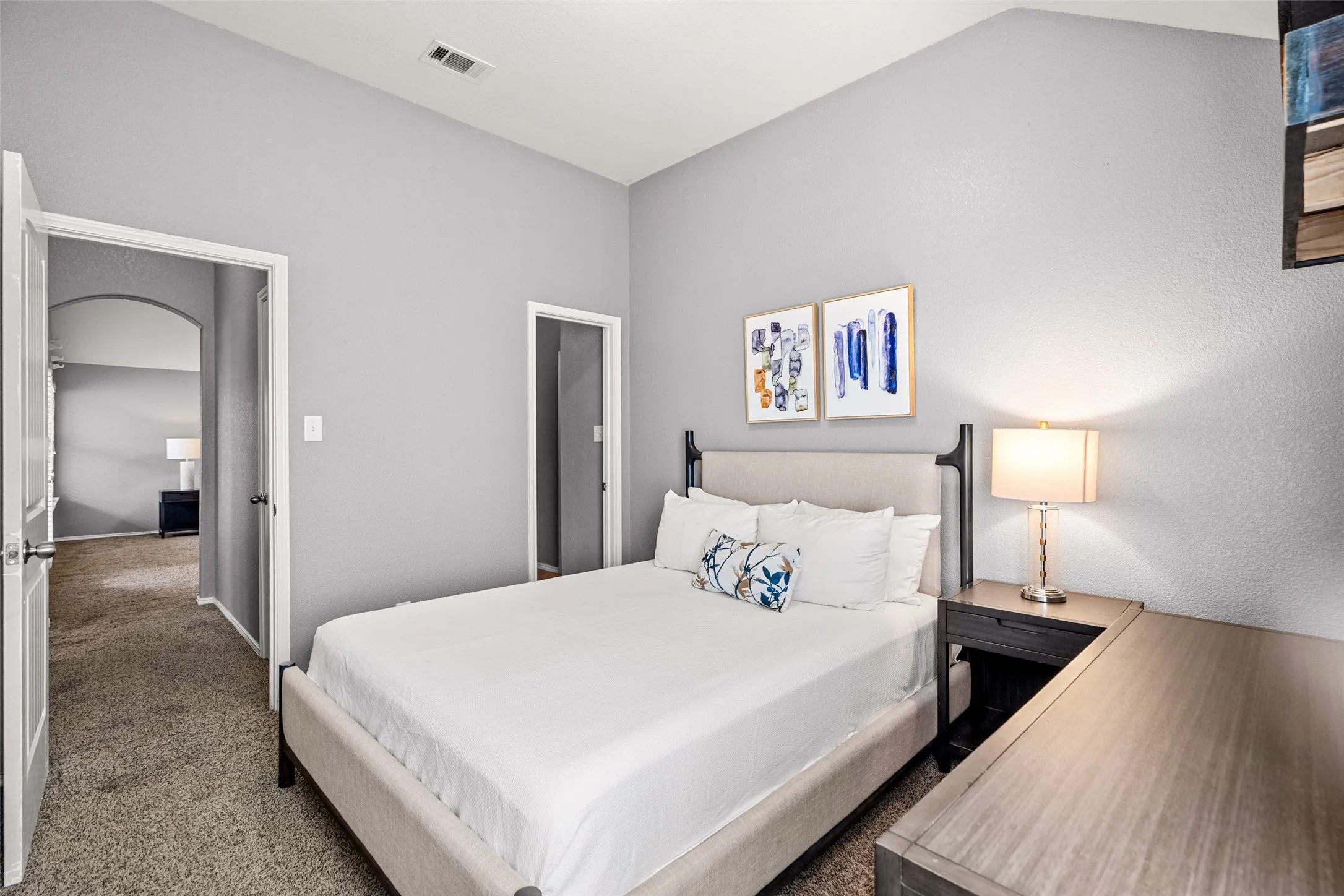 Vaulted ceiling with textured walls and carpet flooring
