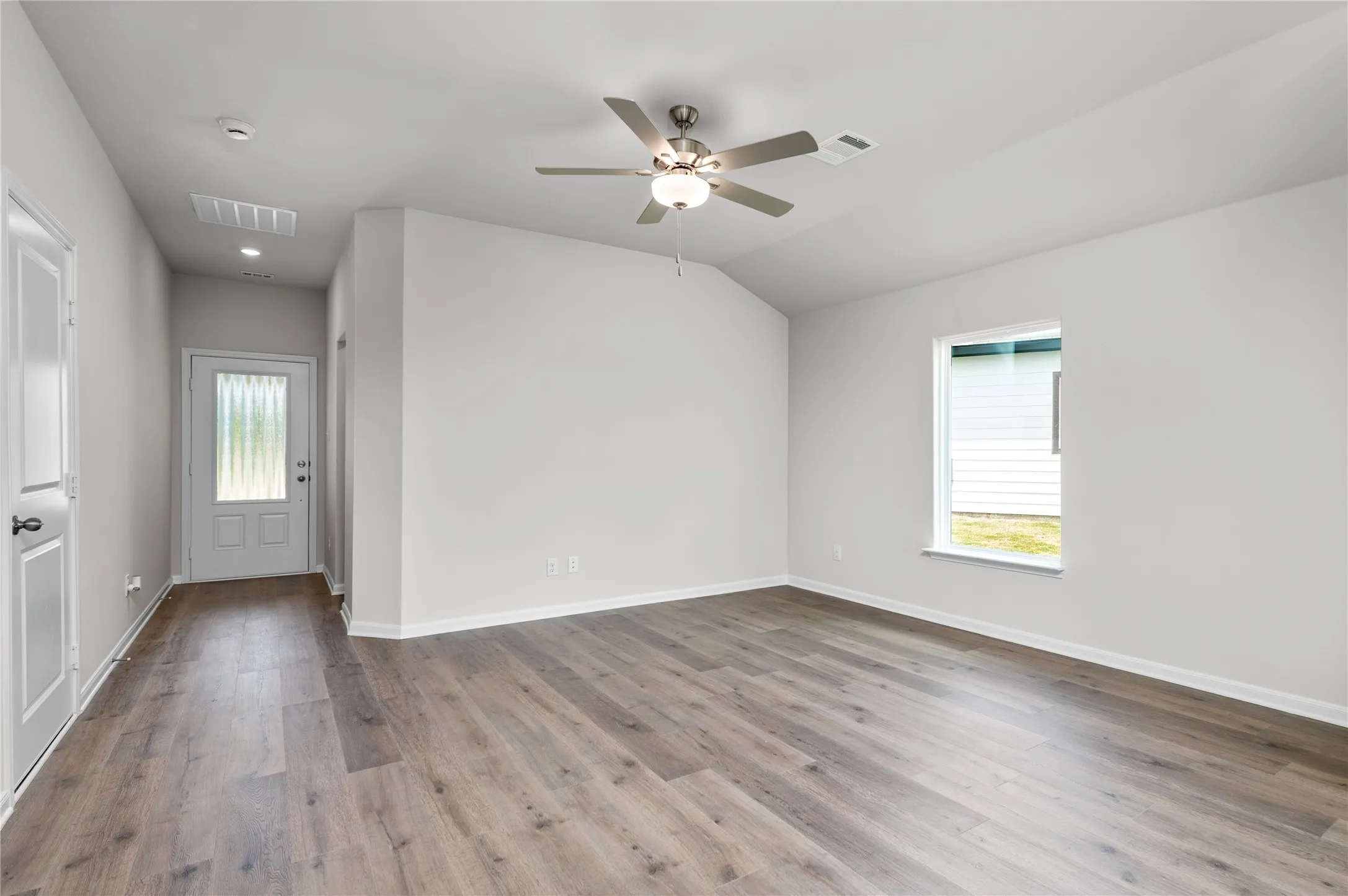 Foyer with light wood-type flooring, healthy amount of natural light, ceiling fan, and lofted ceiling