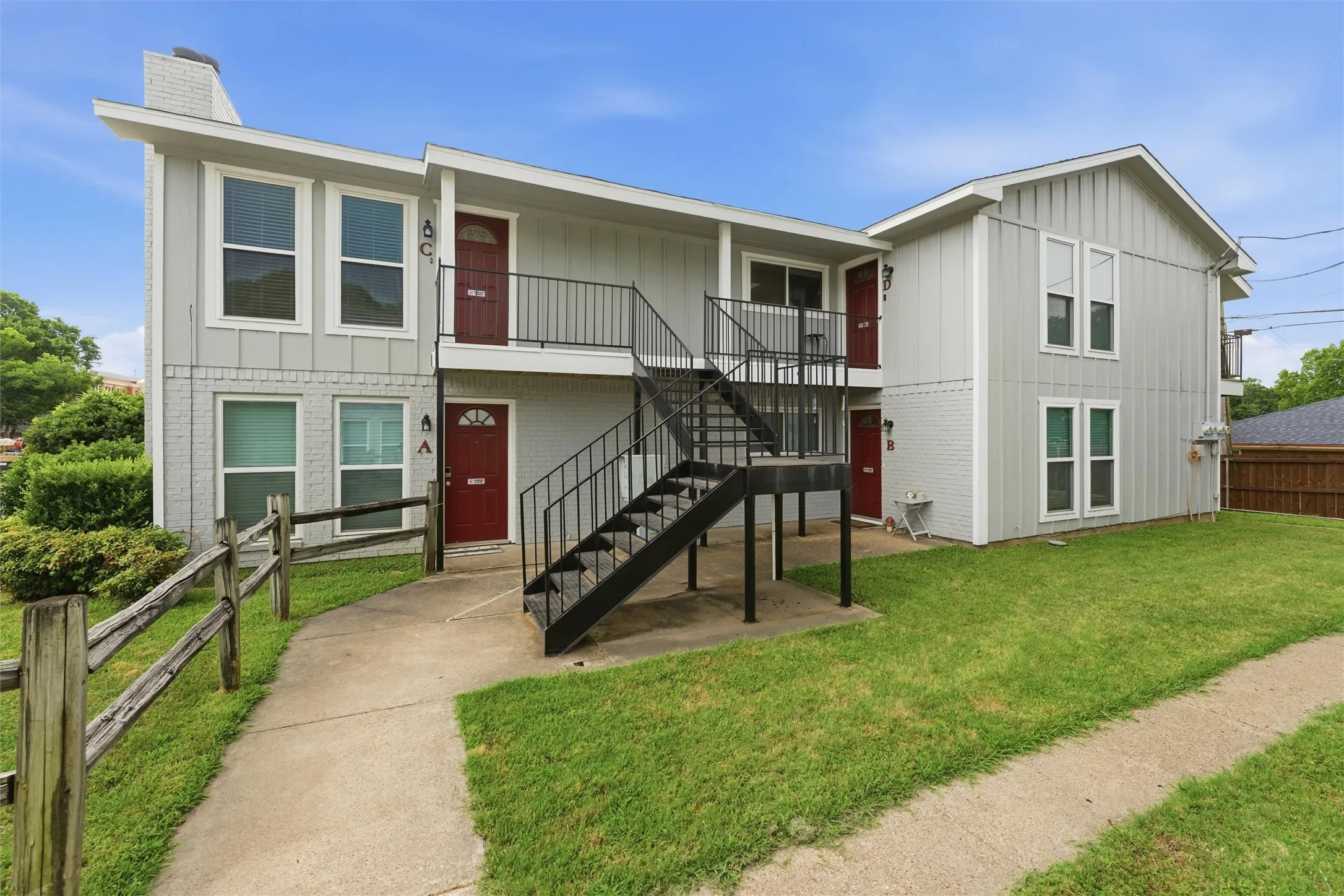 Multi-unit building featuring a light gray exterior, red entry doors, and black metal stairways