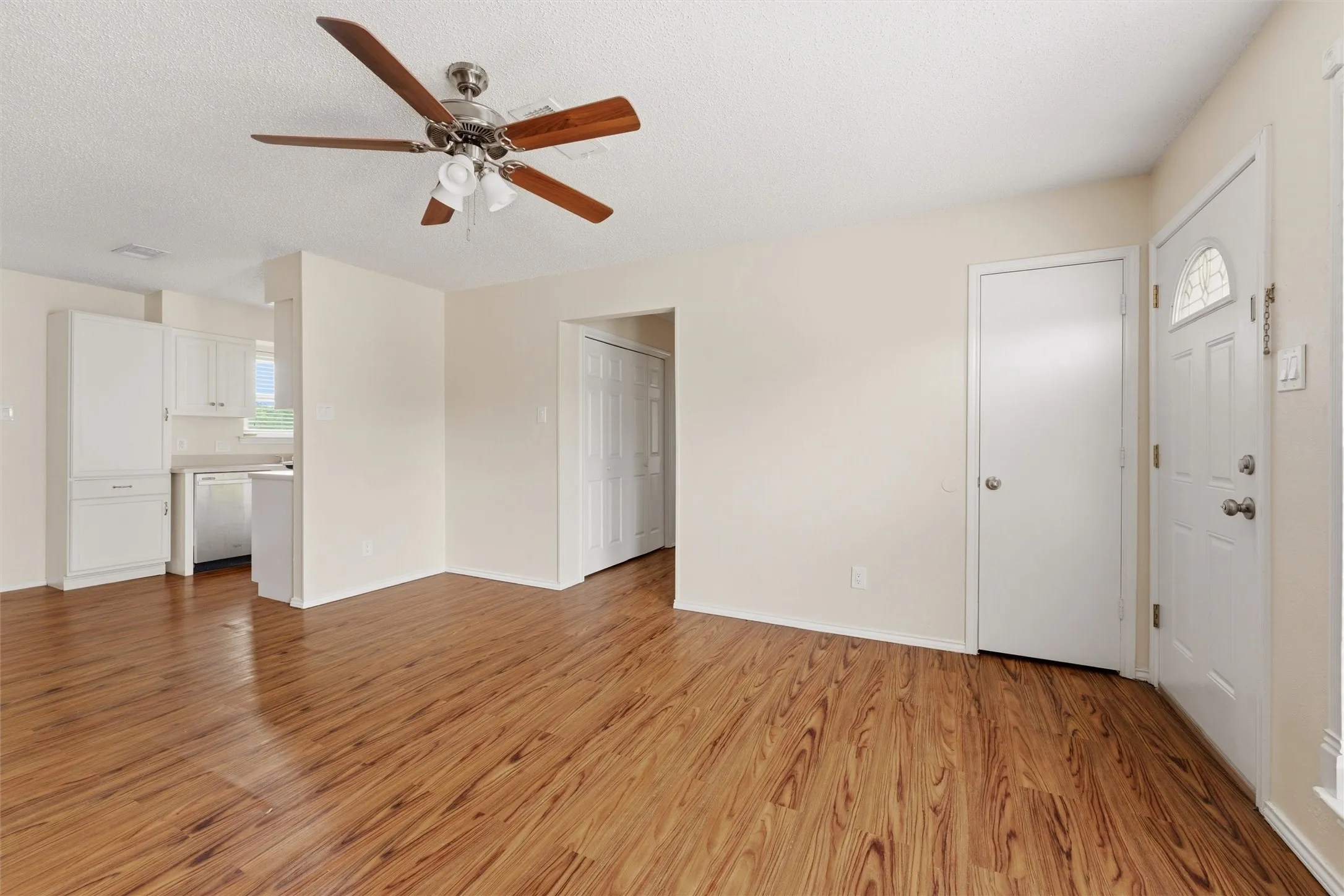 Wood-finish flooring throughout, bright white walls, and a ceiling fan with light fixture