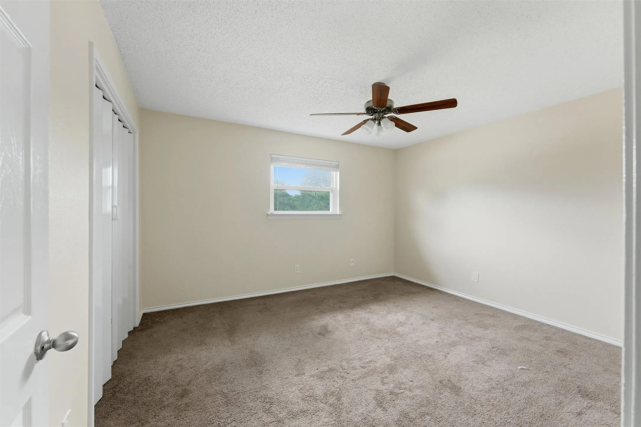 Neutral wall paint, carpet flooring, a ceiling fan, and a window