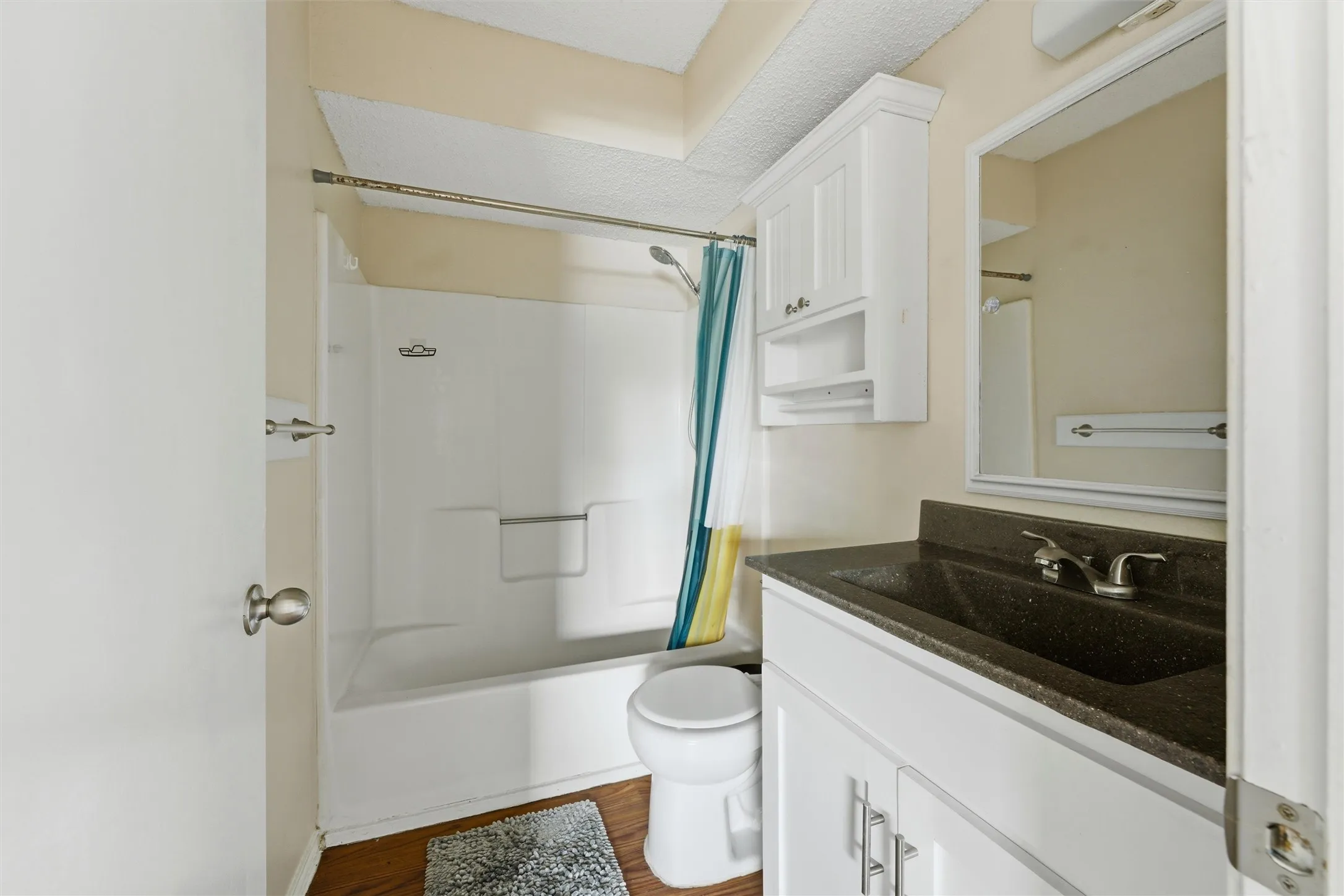 Bathroom featuring a white vanity with a dark countertop, an integrated sink, a white medicine cabinet, and a white tub/shower combination