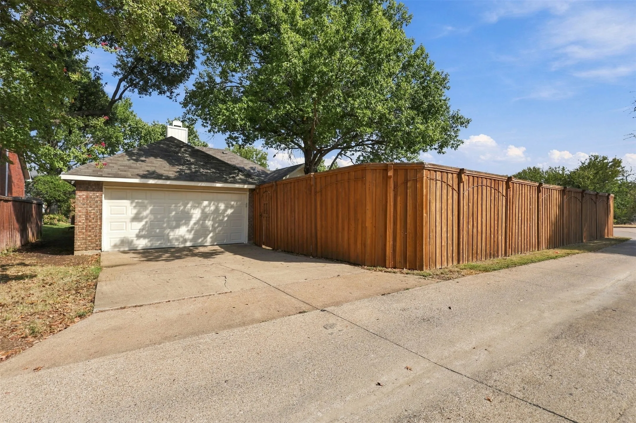 Attached two-car garage with a concrete driveway, brick exterior detailing, and a shingle roof