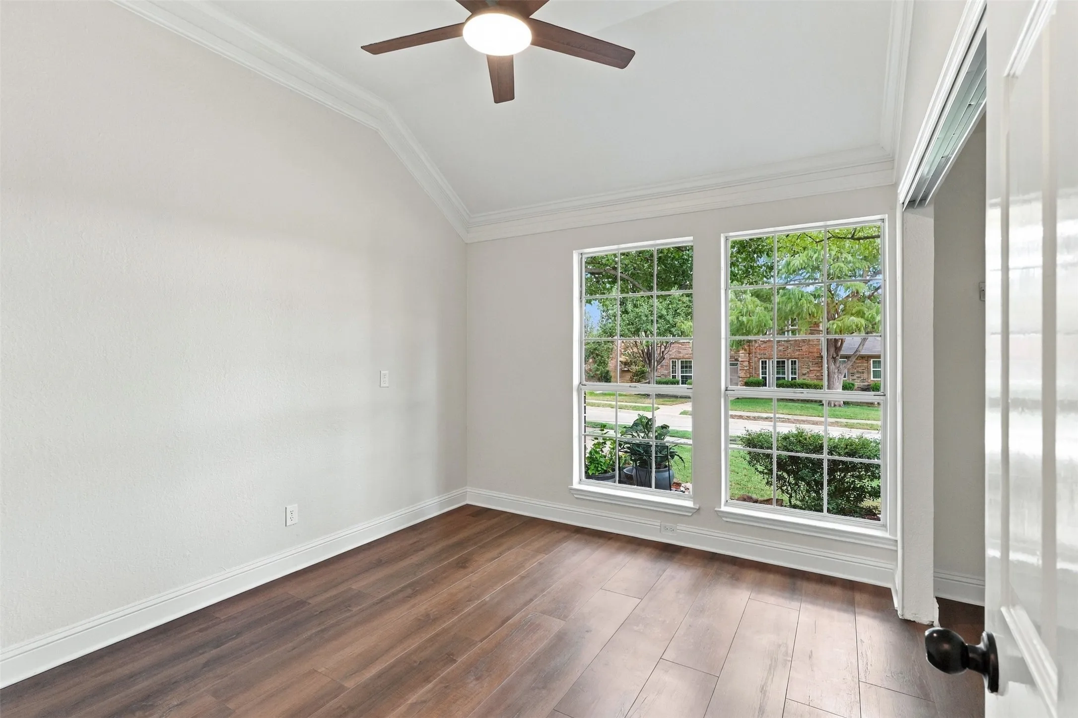 Vaulted ceiling with crown molding, wood-finish flooring, and two double-hung windows
