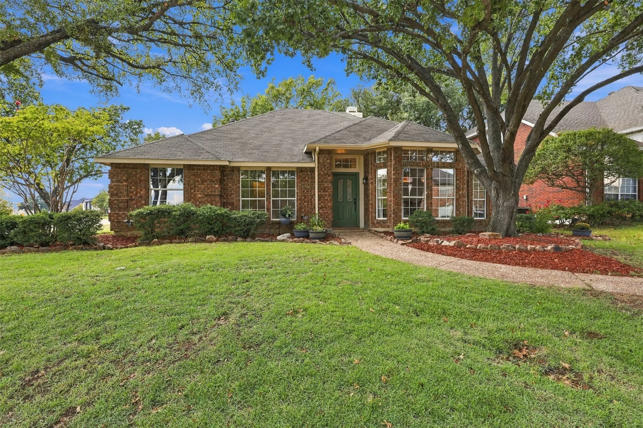 Brick exterior, mature trees, expansive front lawn, curved walkway, bay windows