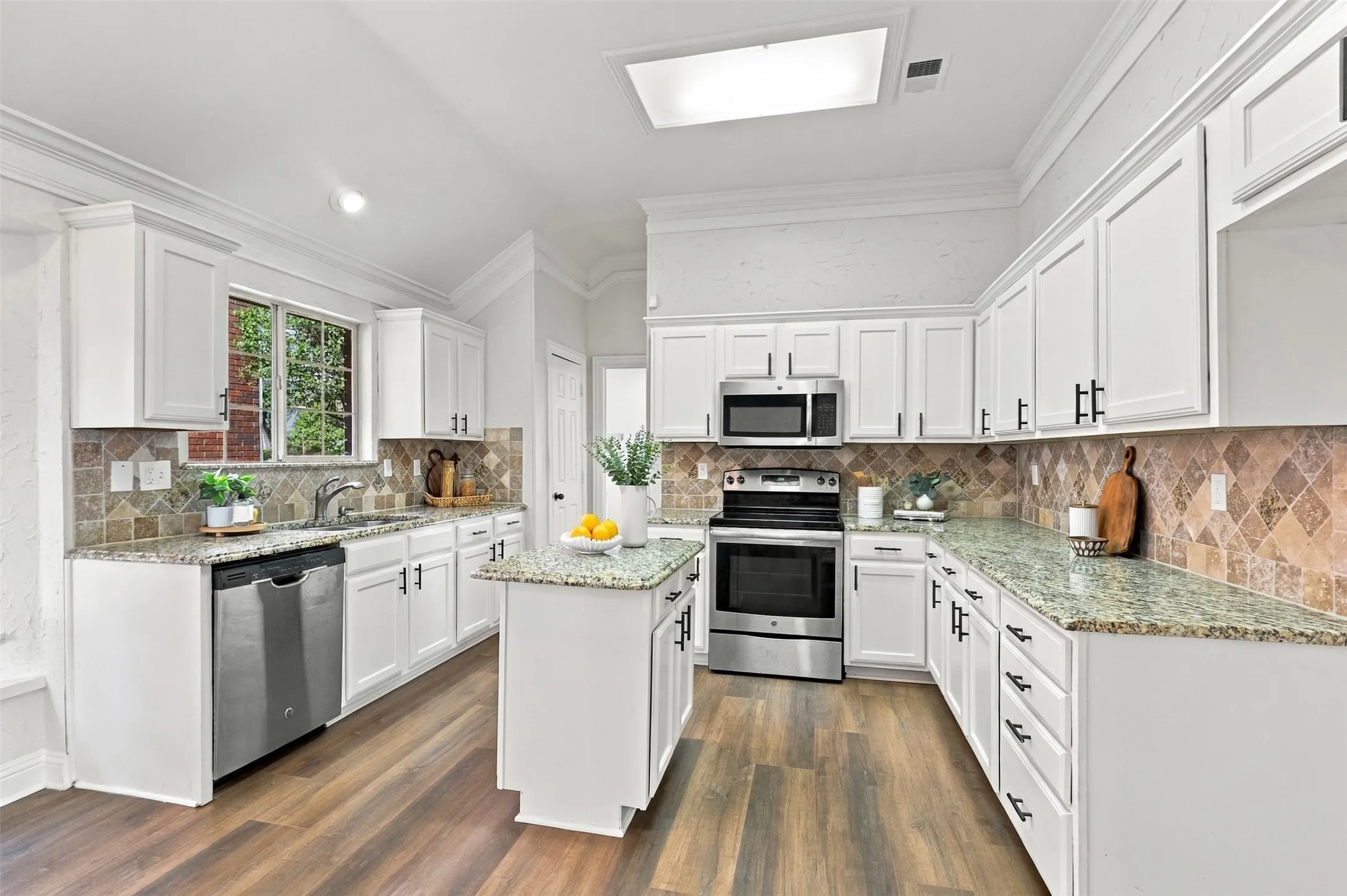 White cabinetry with dark hardware, stainless steel appliances, granite countertops, a tiled backsplash, and wood-finish flooring