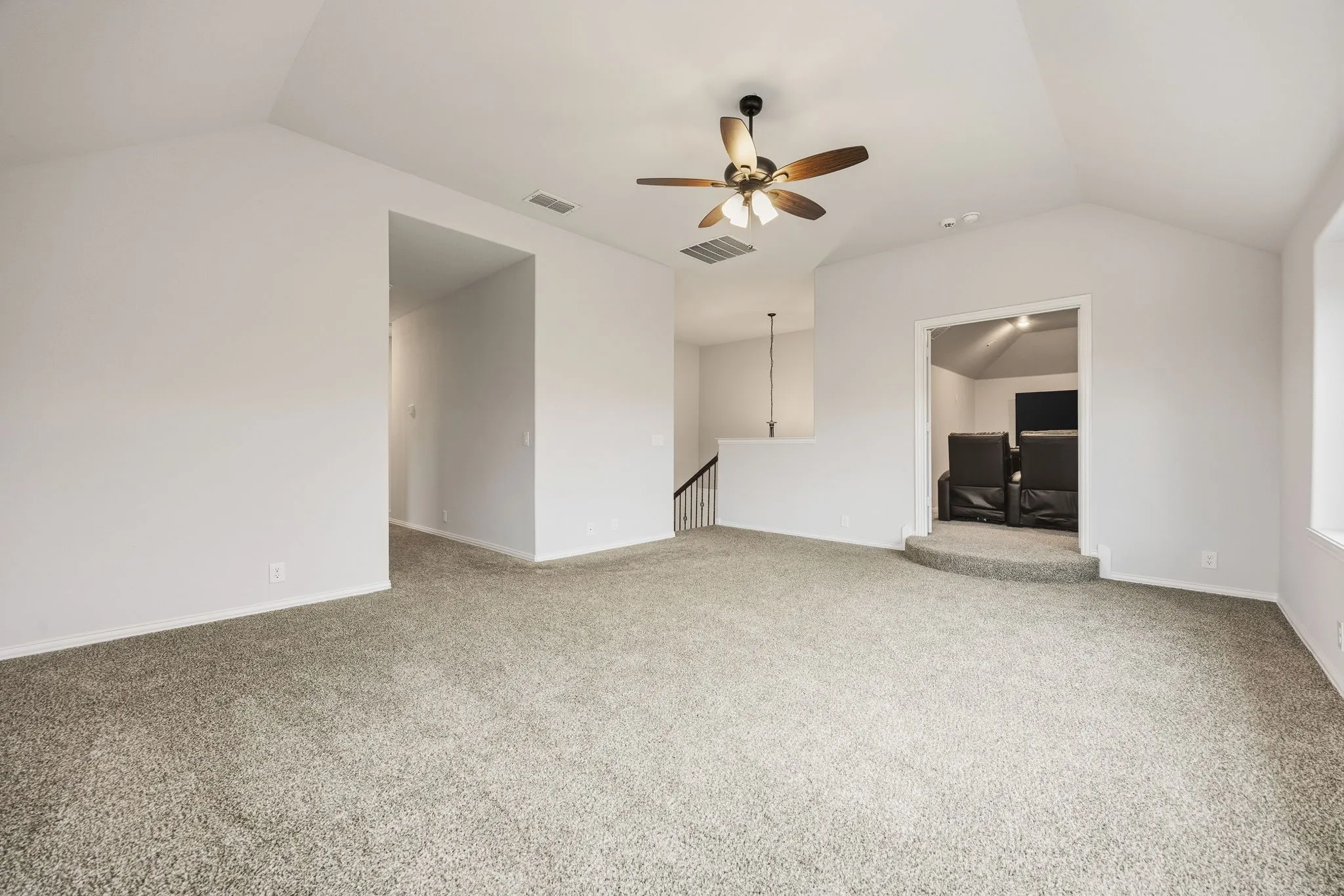 Vaulted ceiling, ceiling fan, carpet flooring, dedicated media area, open architectural elements