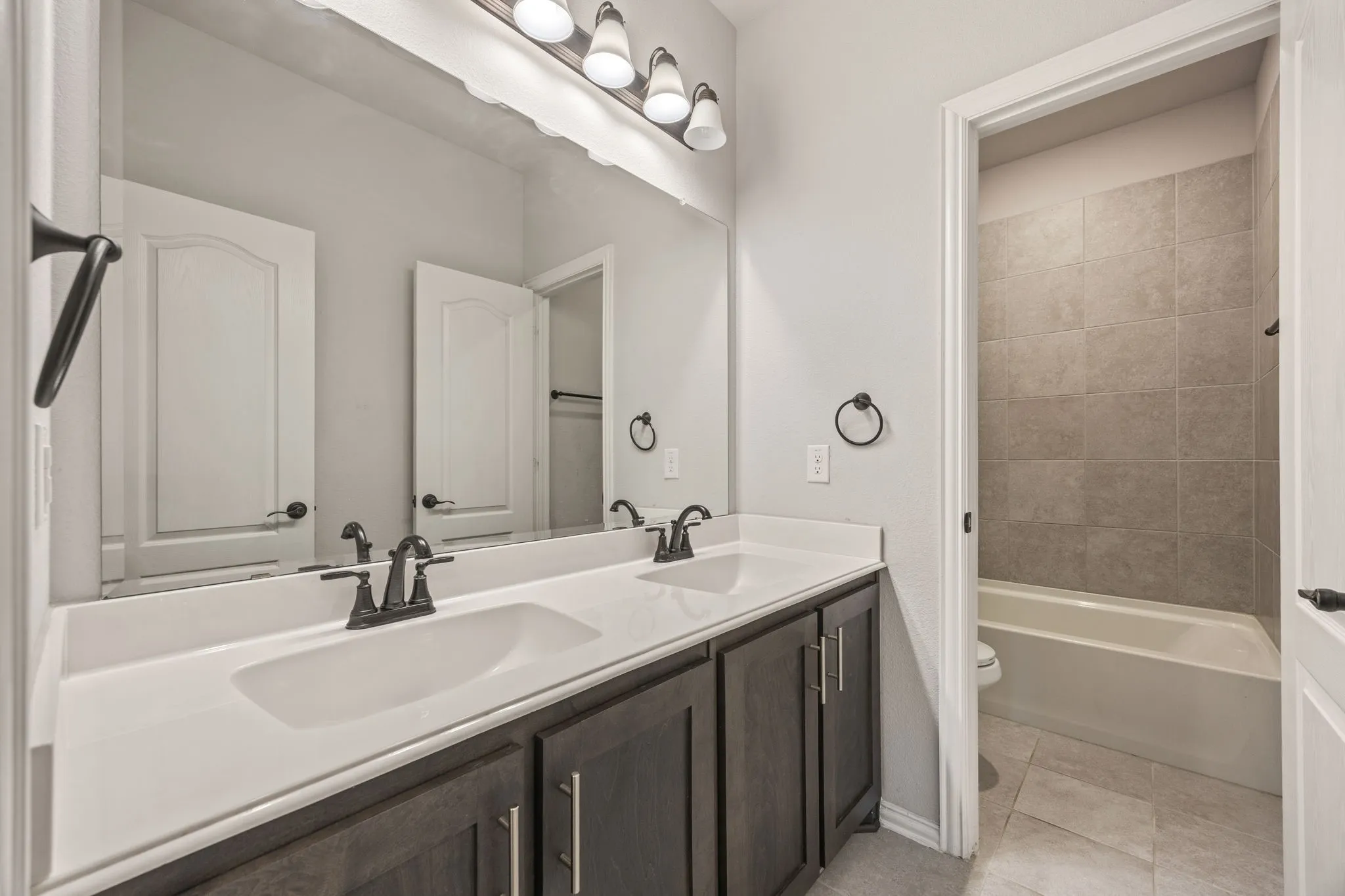 Upstairs double vanity bathroom, dark wood-finish cabinetry, and matte black fixtures