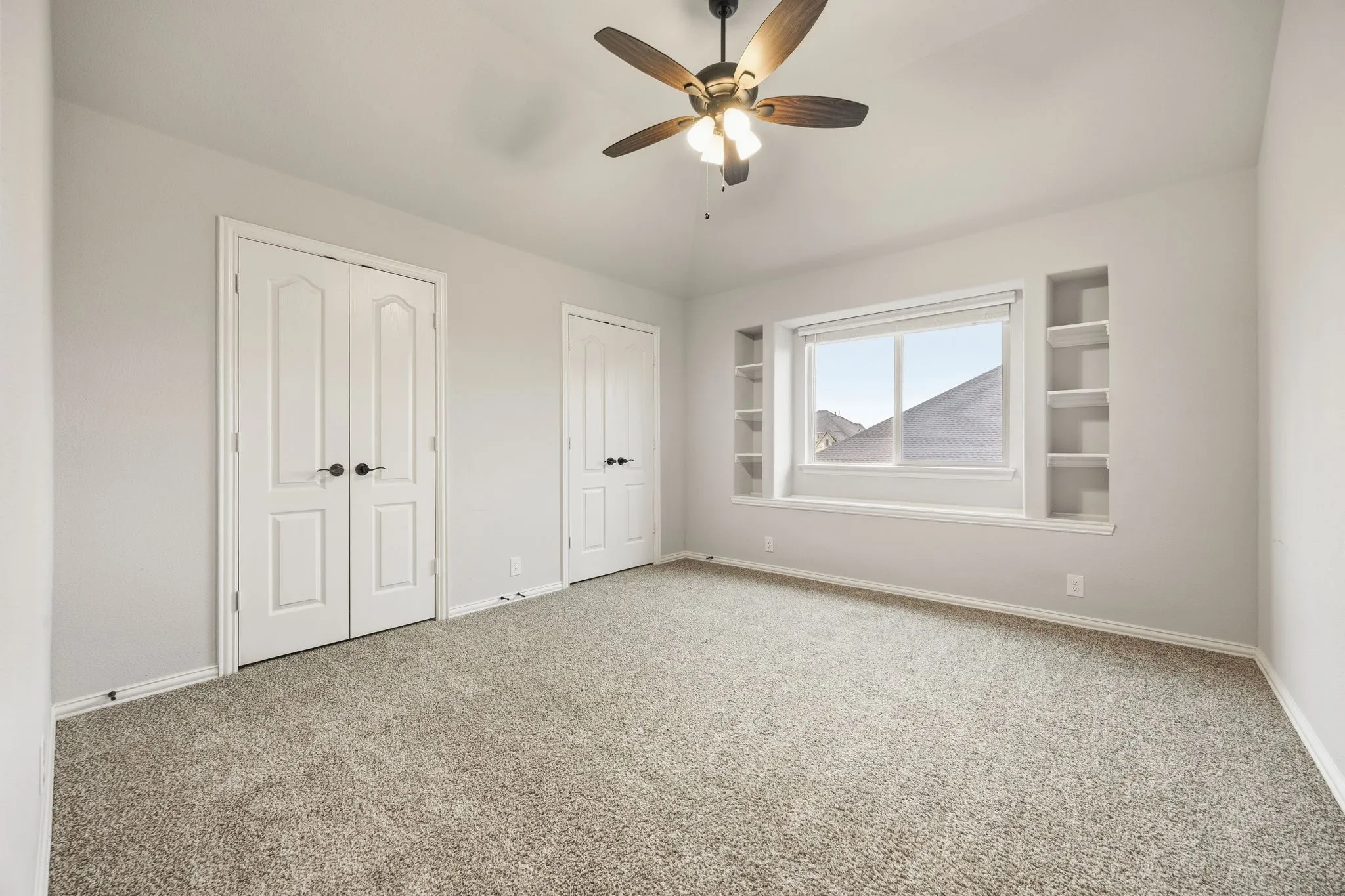 Recessed window with built-in shelving, ceiling fan with integrated lighting, and carpet flooring
