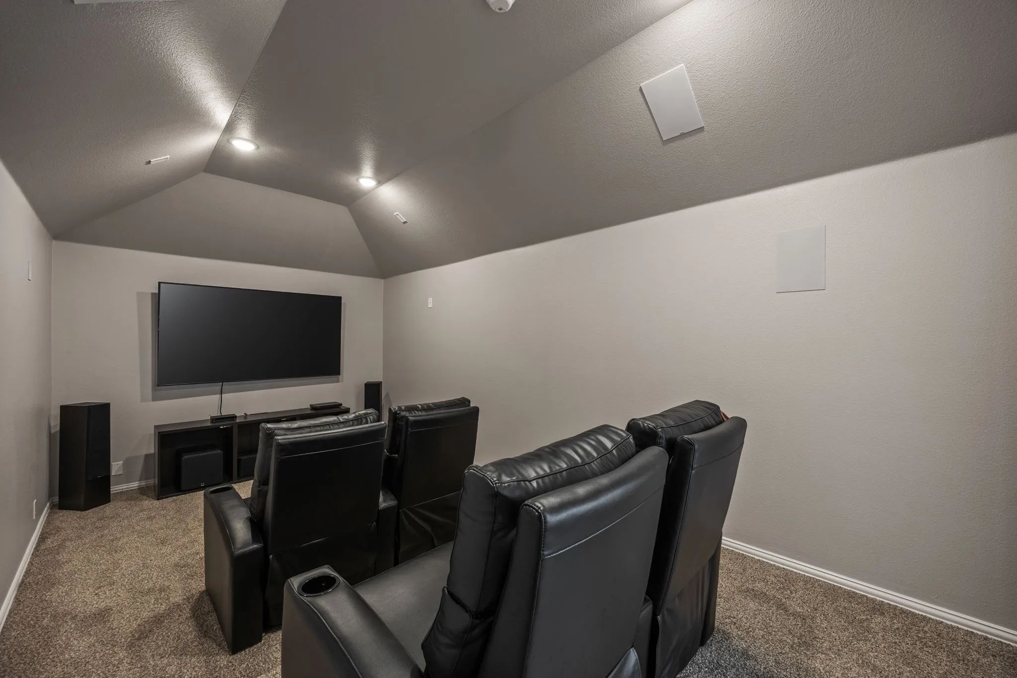Media room featuring a vaulted ceiling with recessed lighting, wall-mounted speakers, and carpet flooring