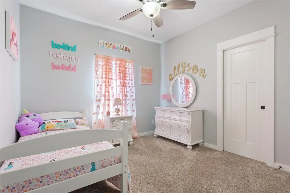 Carpeted flooring, ceiling fan, white paneled door with dark hardware, and light-colored walls