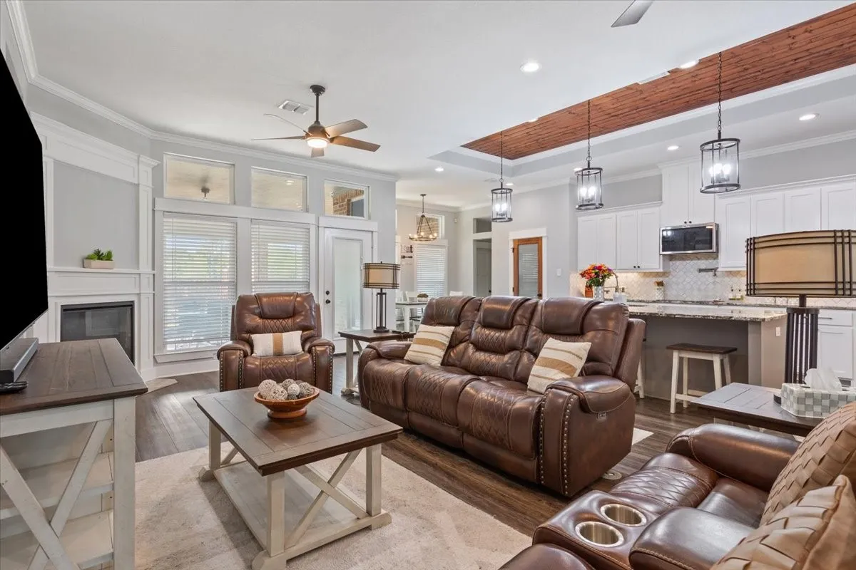 Living area featuring wood-finish flooring, a fireplace with a white mantel, and ceiling fan