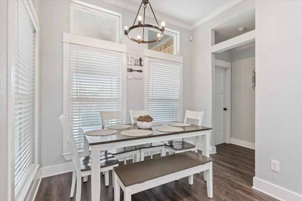 Recessed dining space featuring a contemporary chandelier, wood-finish flooring, and crown molding