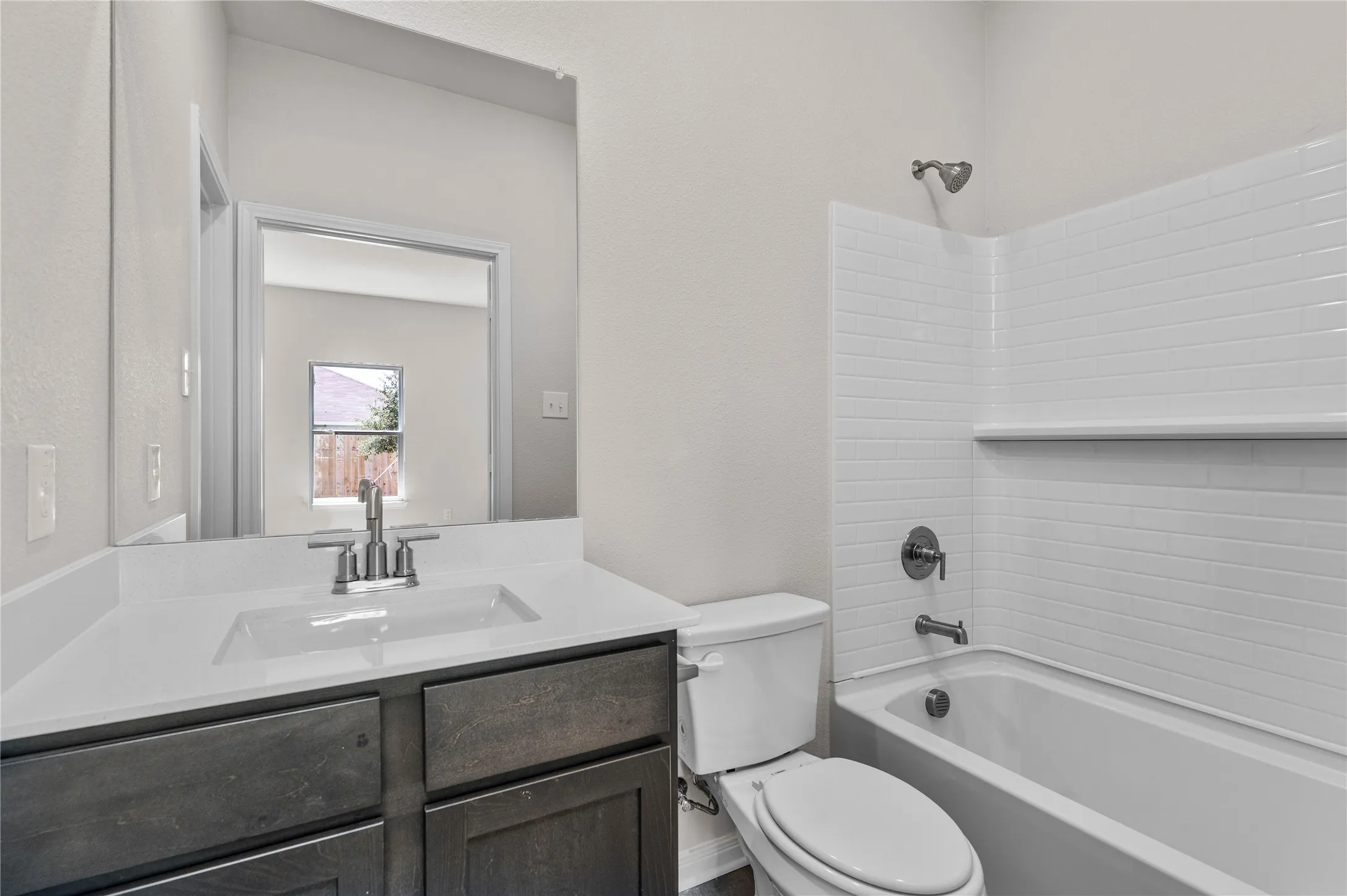 Full bath with  shower combination, vanity, and a textured wall