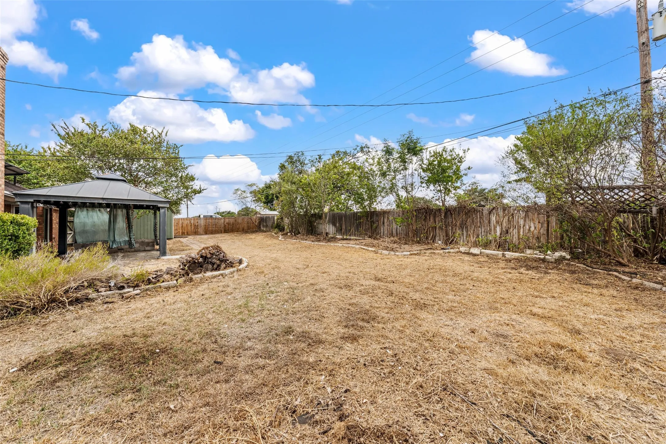 Spacious backyard featuring a gazebo, fenced perimeter, and mature trees
