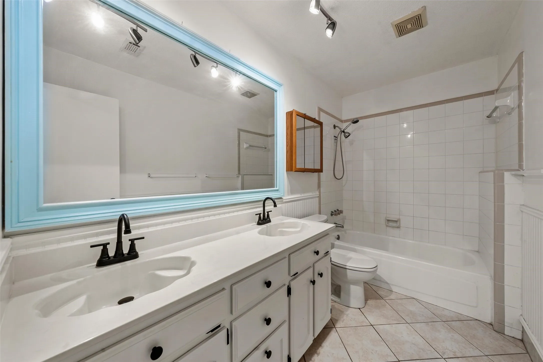 Double vanity with integrated sinks, matte black faucets, and track lighting