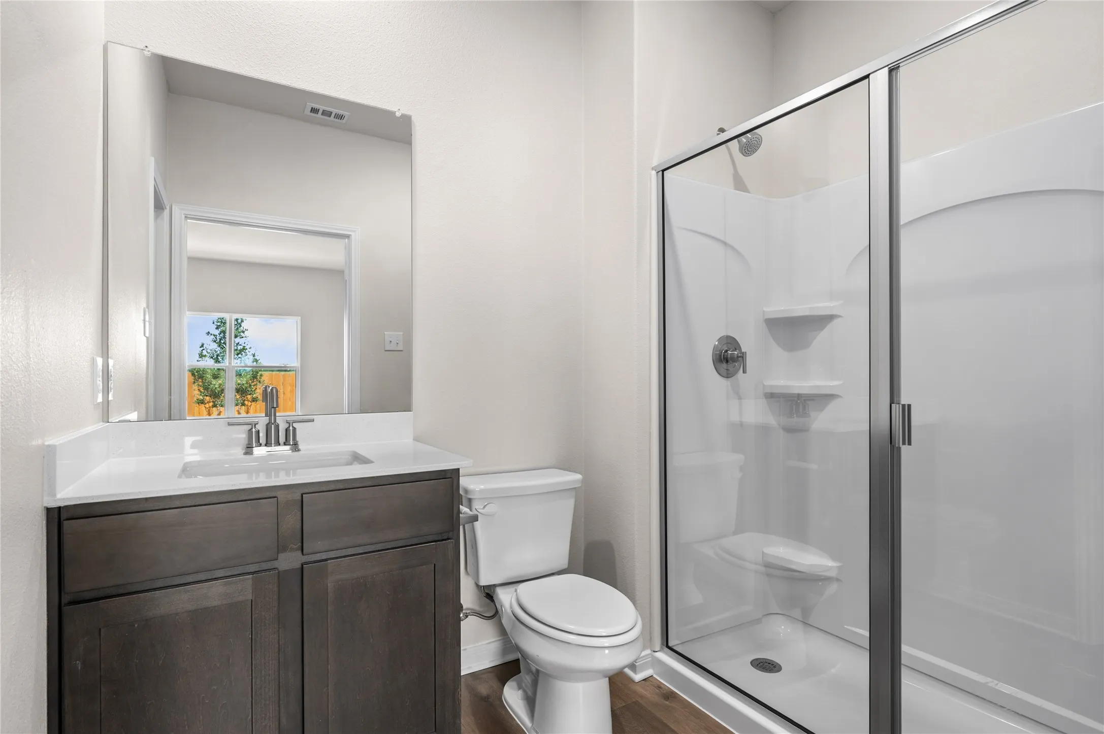 Full bathroom featuring a stall shower, vanity, and dark wood-type flooring