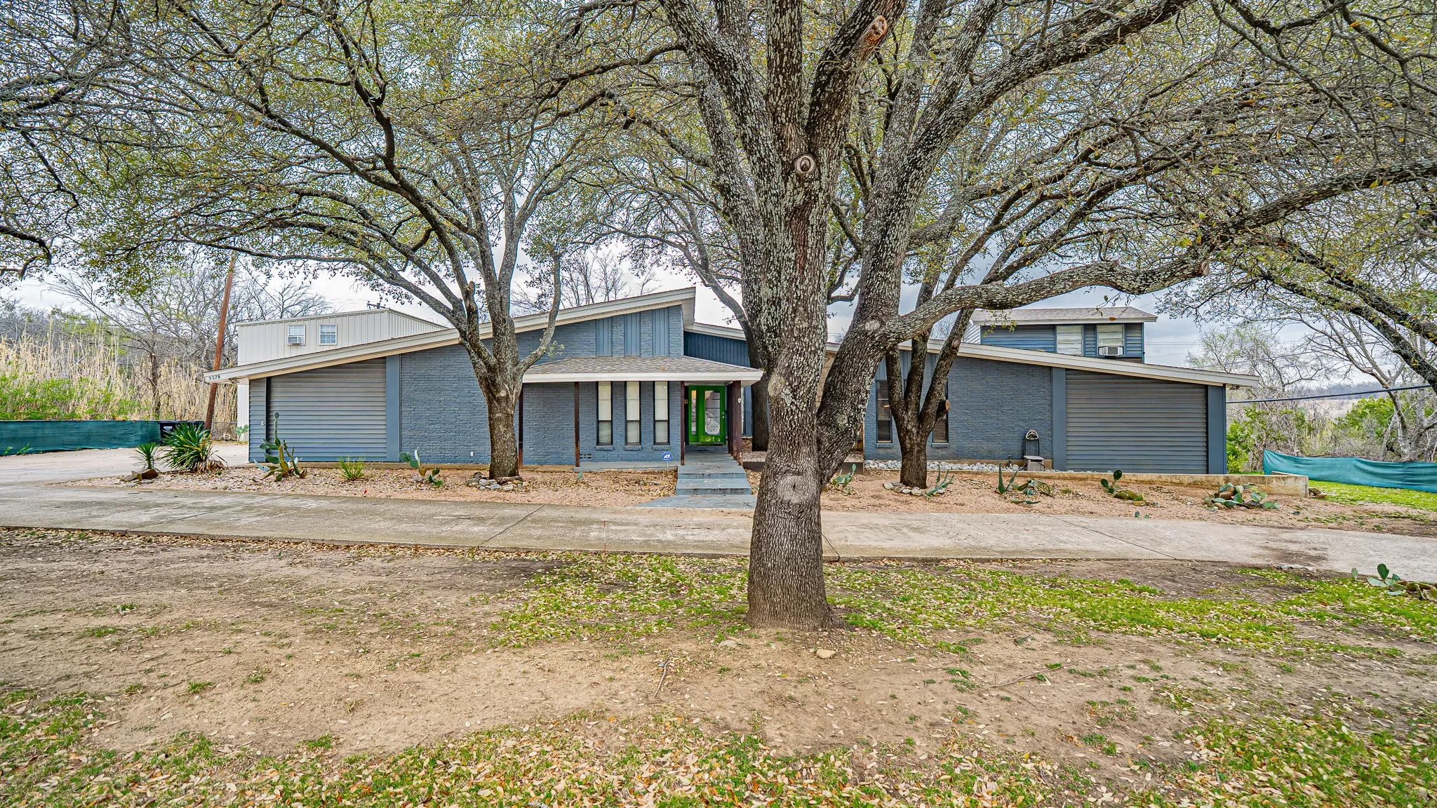 Front of House with mature trees on property