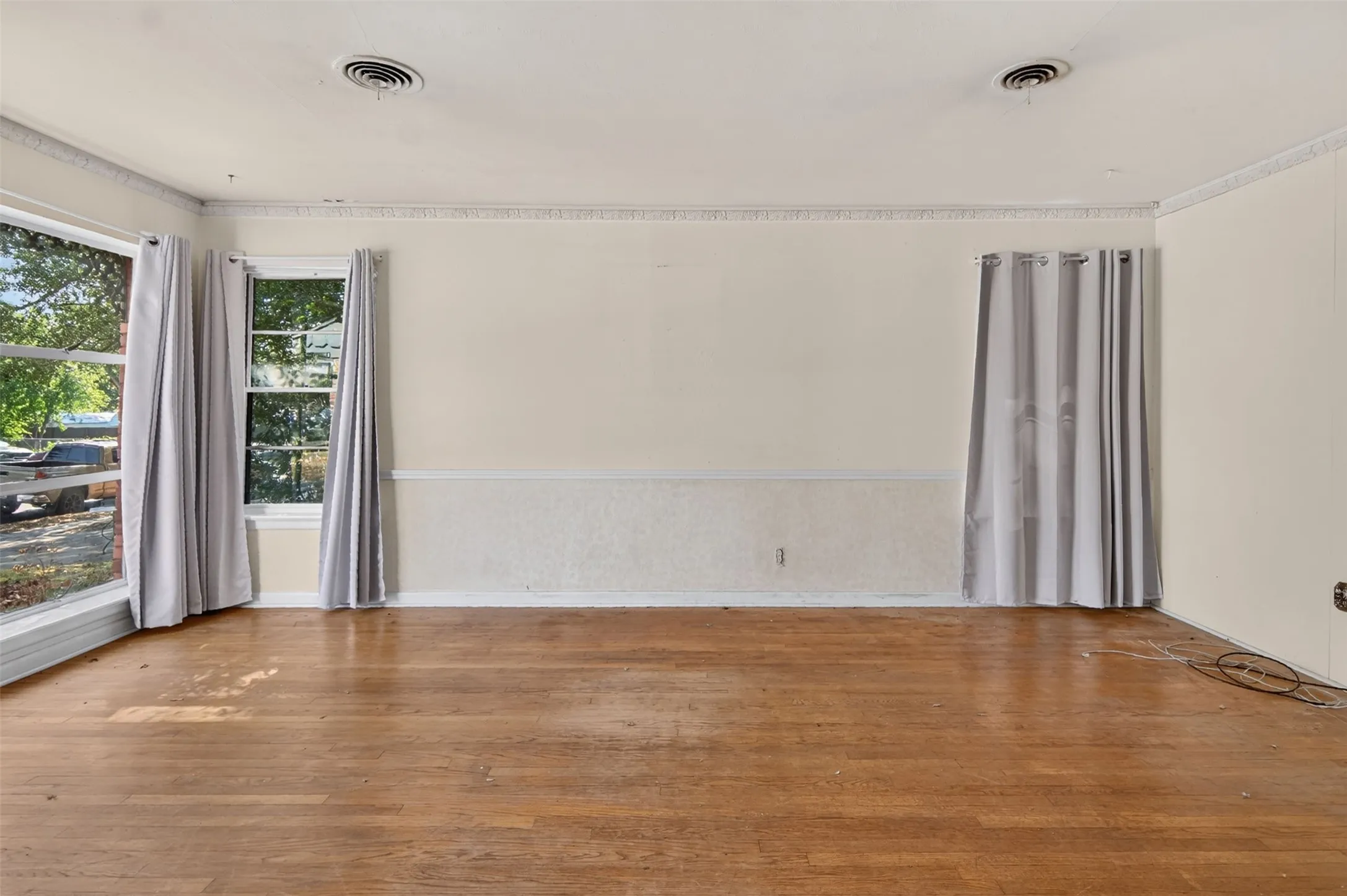 Wood-finish flooring with multiple windows and crown molding