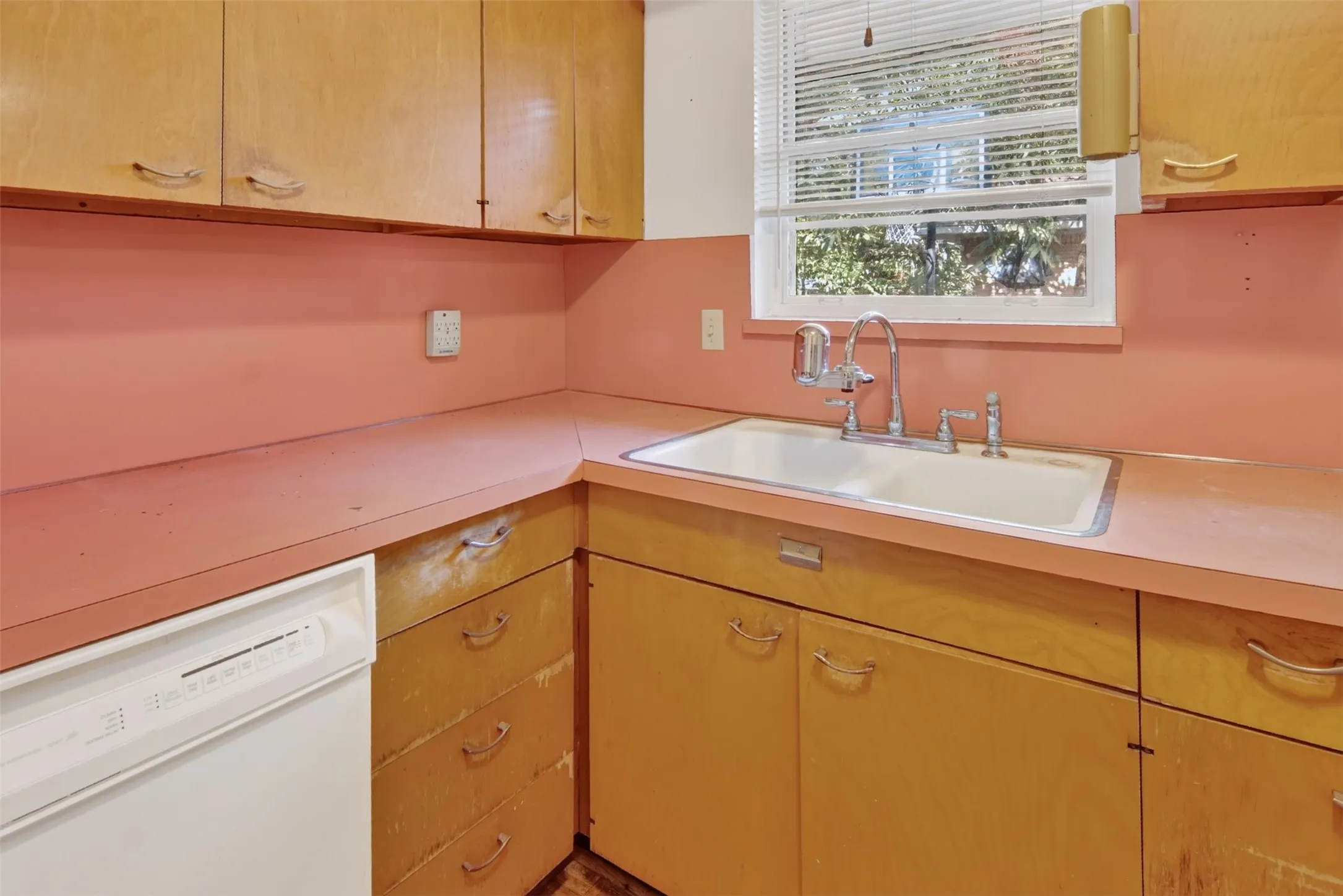 Kitchen featuring wood-finish cabinetry, a double-basin sink with chrome fixtures, and a window with blinds