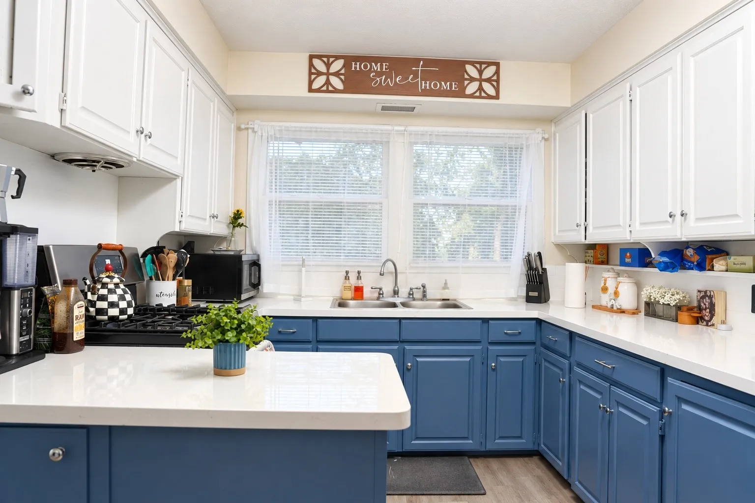Kitchen featuring dual-tone cabinetry, white countertops, and a double-basin stainless steel sink with a gooseneck faucet