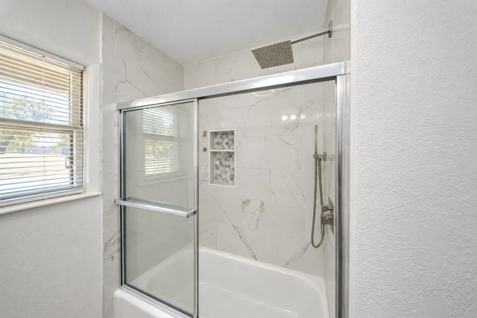 Bathtub with glass shower enclosure and a rain shower head