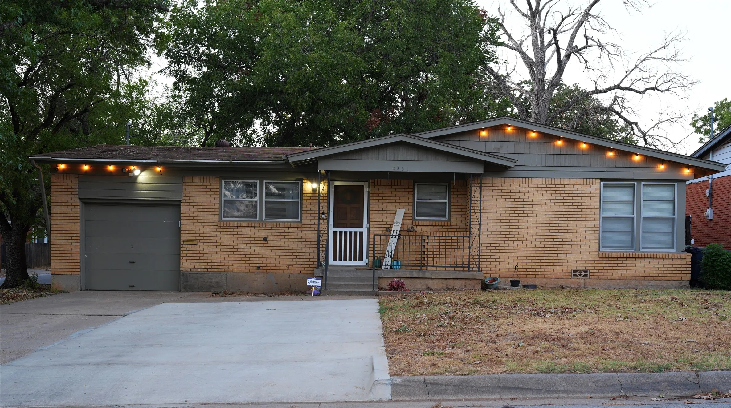 Brick exterior with a covered porch, attached garage, and concrete driveway