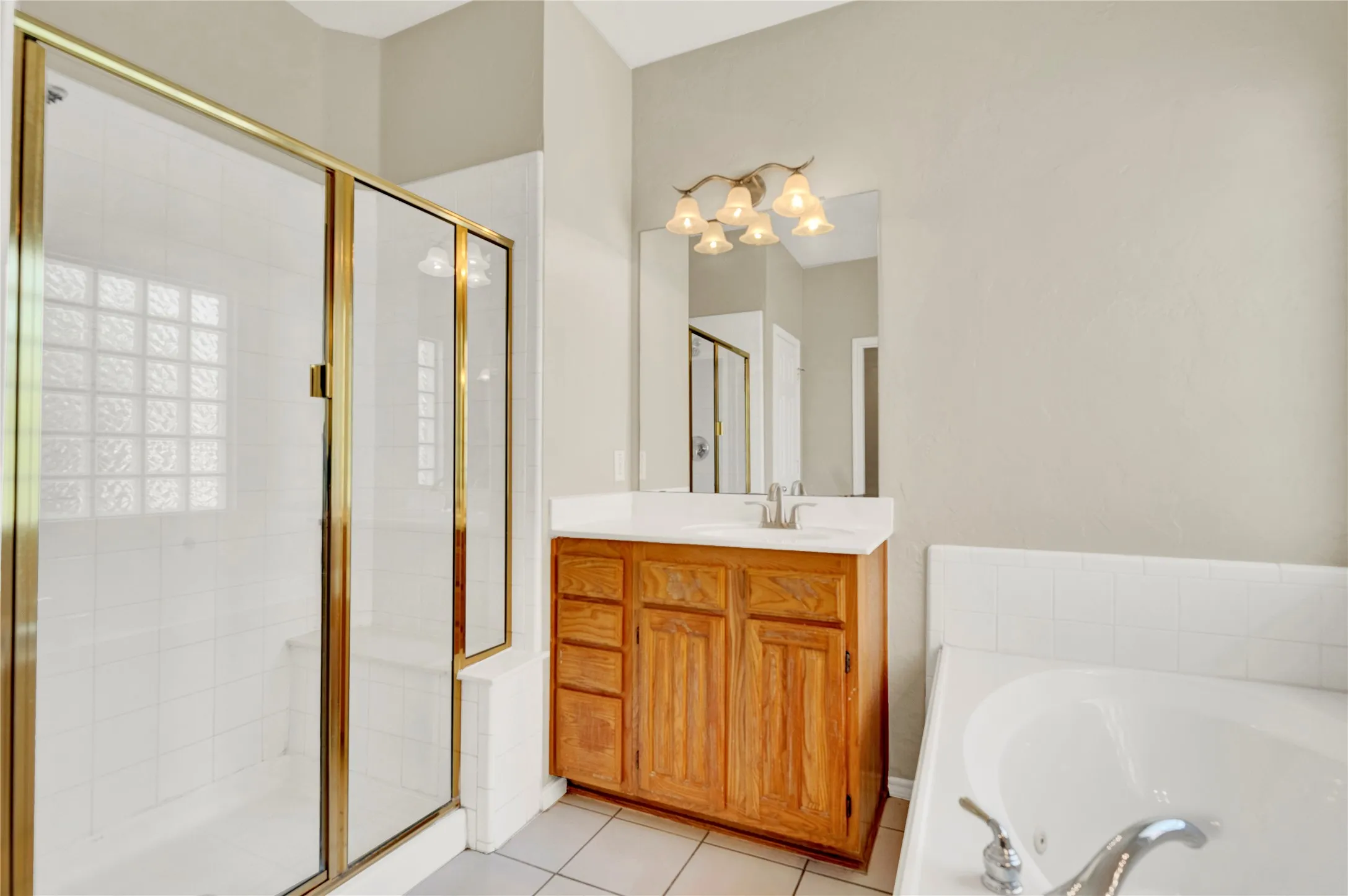 Shower enclosure with gold-finish framing, integrated glass block window, and built-in bench