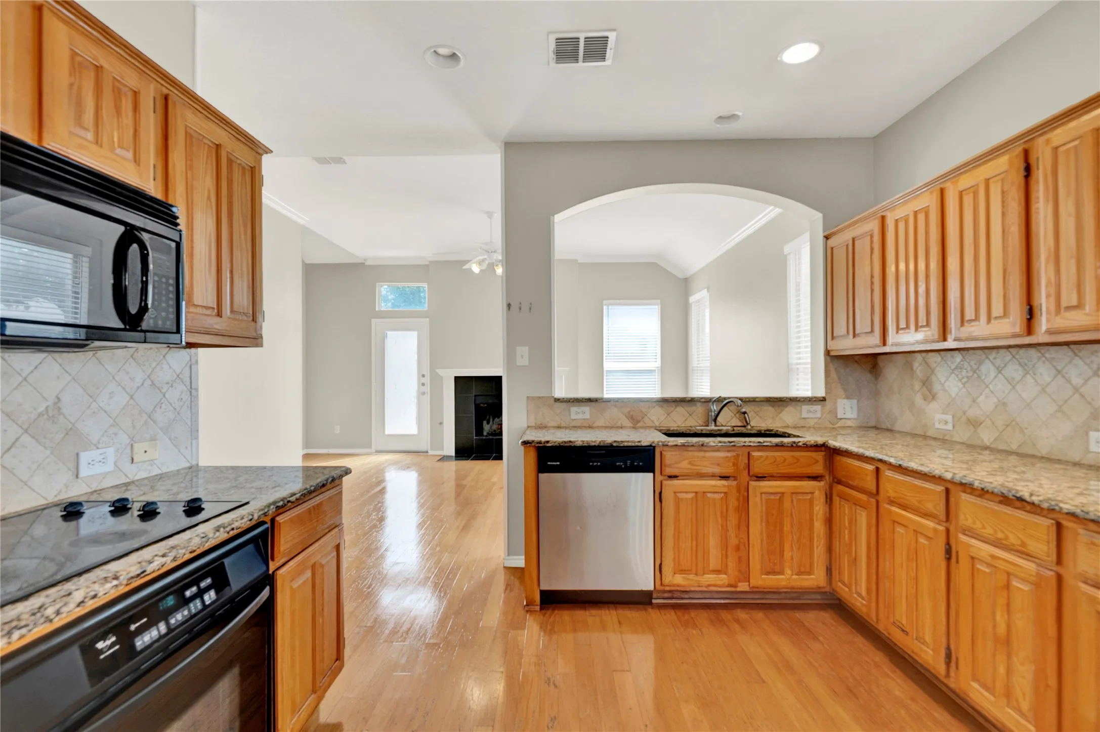 Kitchen featuring wood-finish cabinetry, granite countertops, tile backsplash, and a built-in microwave