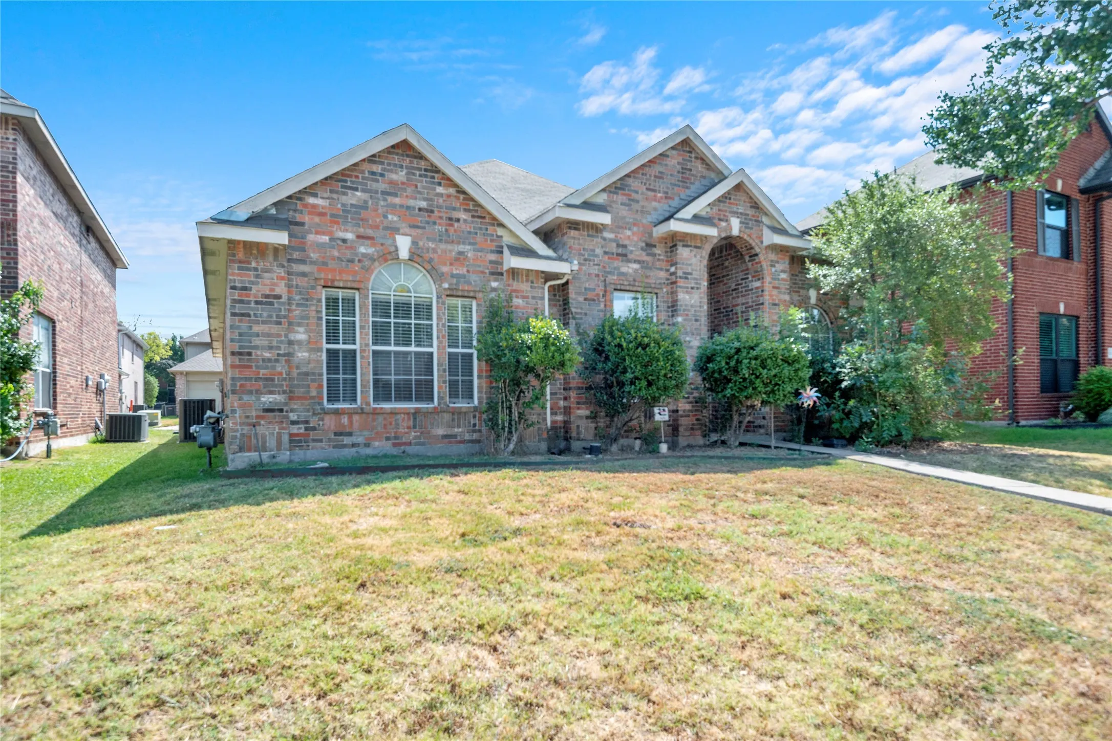 Brick exterior with arched entry and gabled rooflines, featuring a large arched window with grid detailing