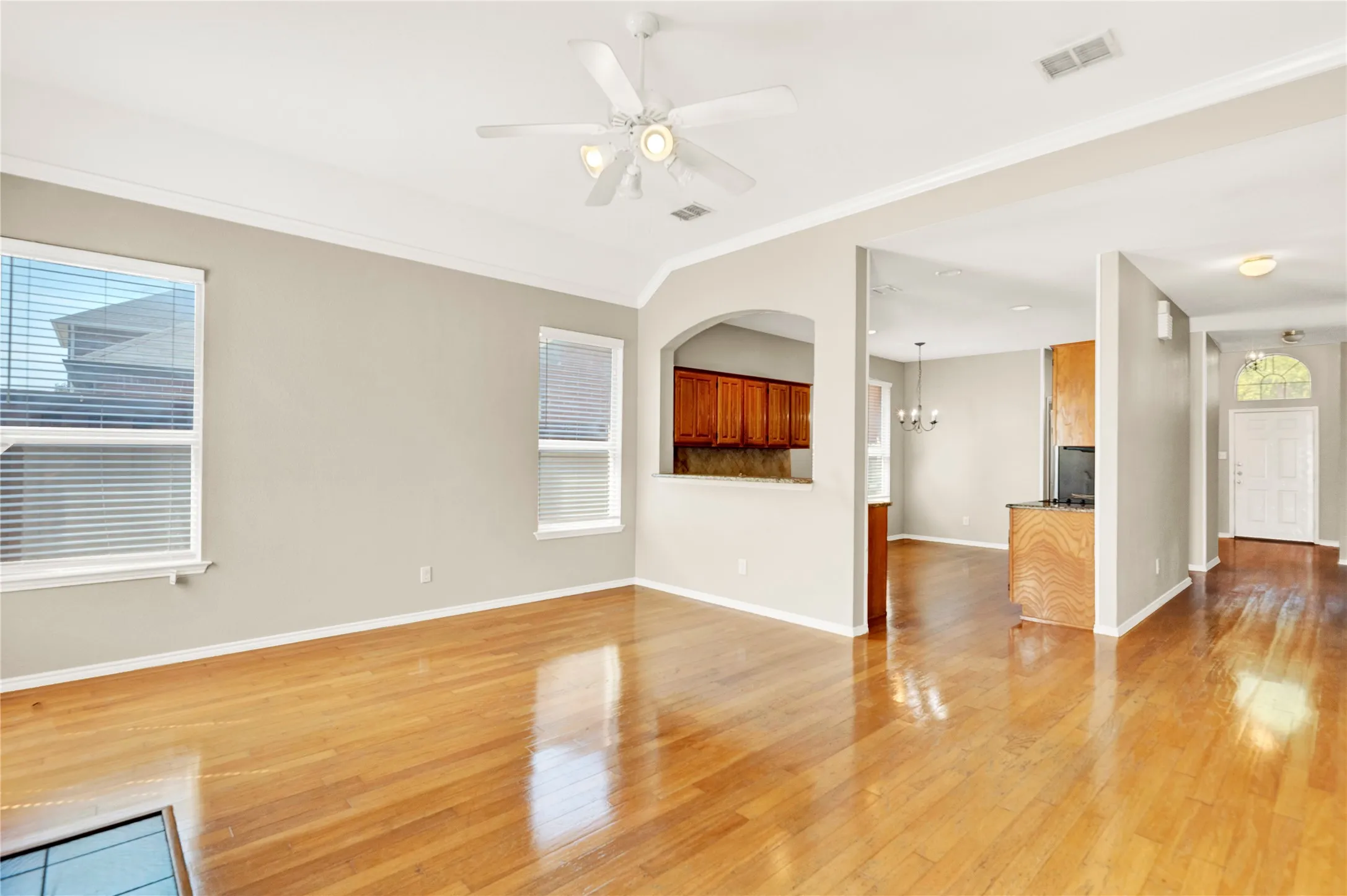 Hardwood-finish flooring, recessed lighting, ceiling fan, pass-through window, and archway architectural detail