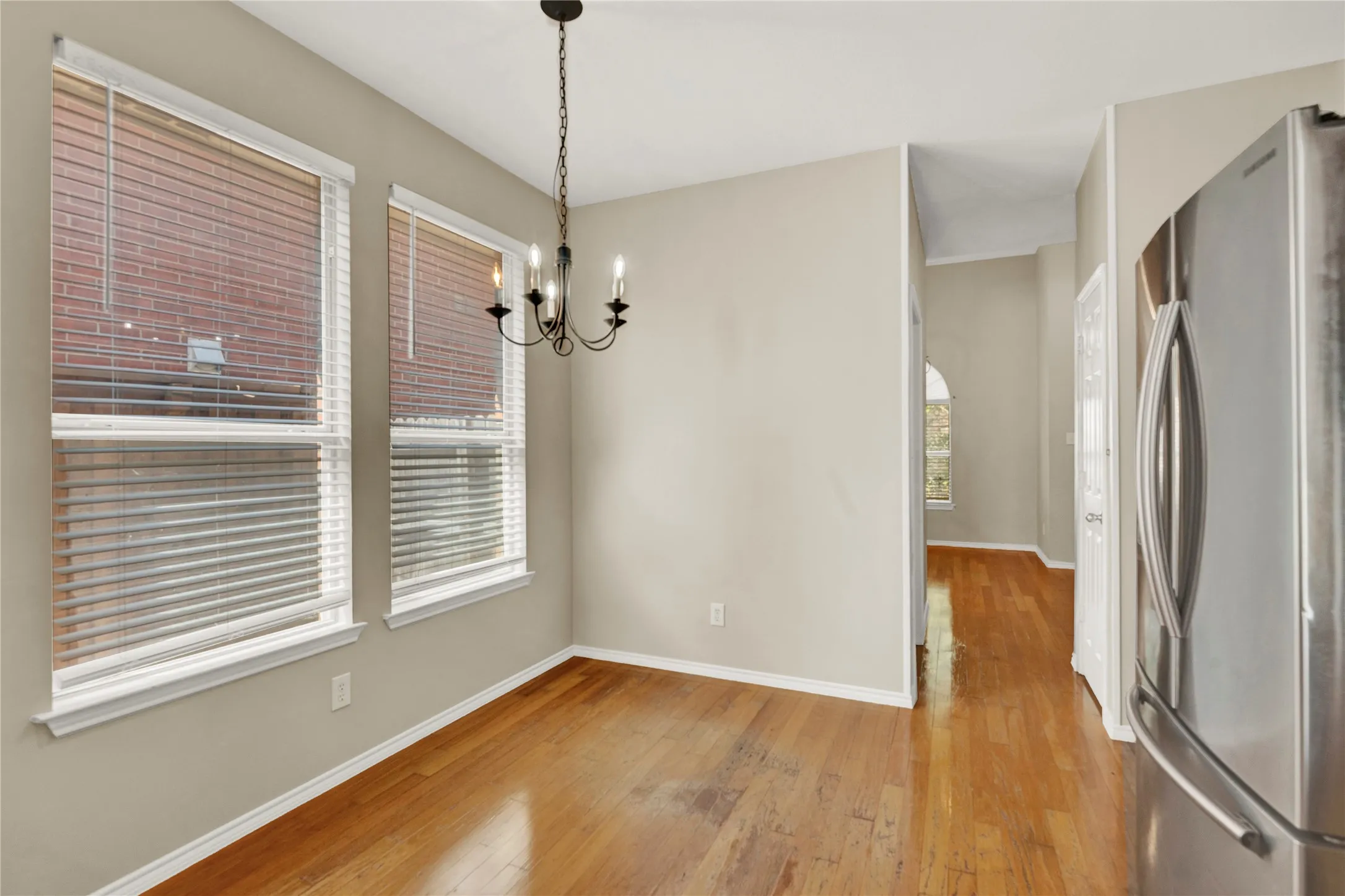 Hardwood-finish flooring, recessed windows with blinds, and a black wrought iron chandelier