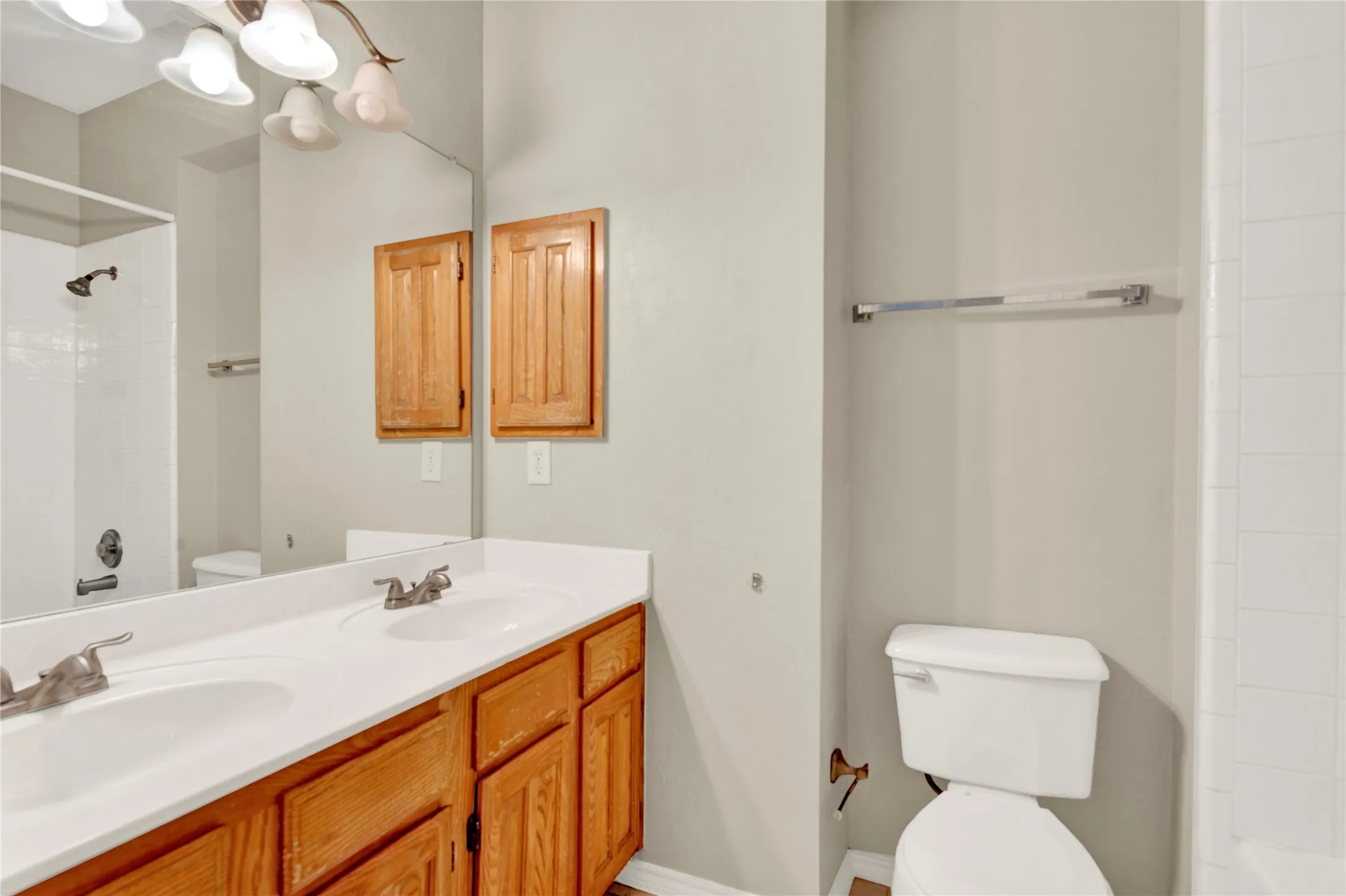 Dual sink vanity with wood-finish cabinetry and white countertops