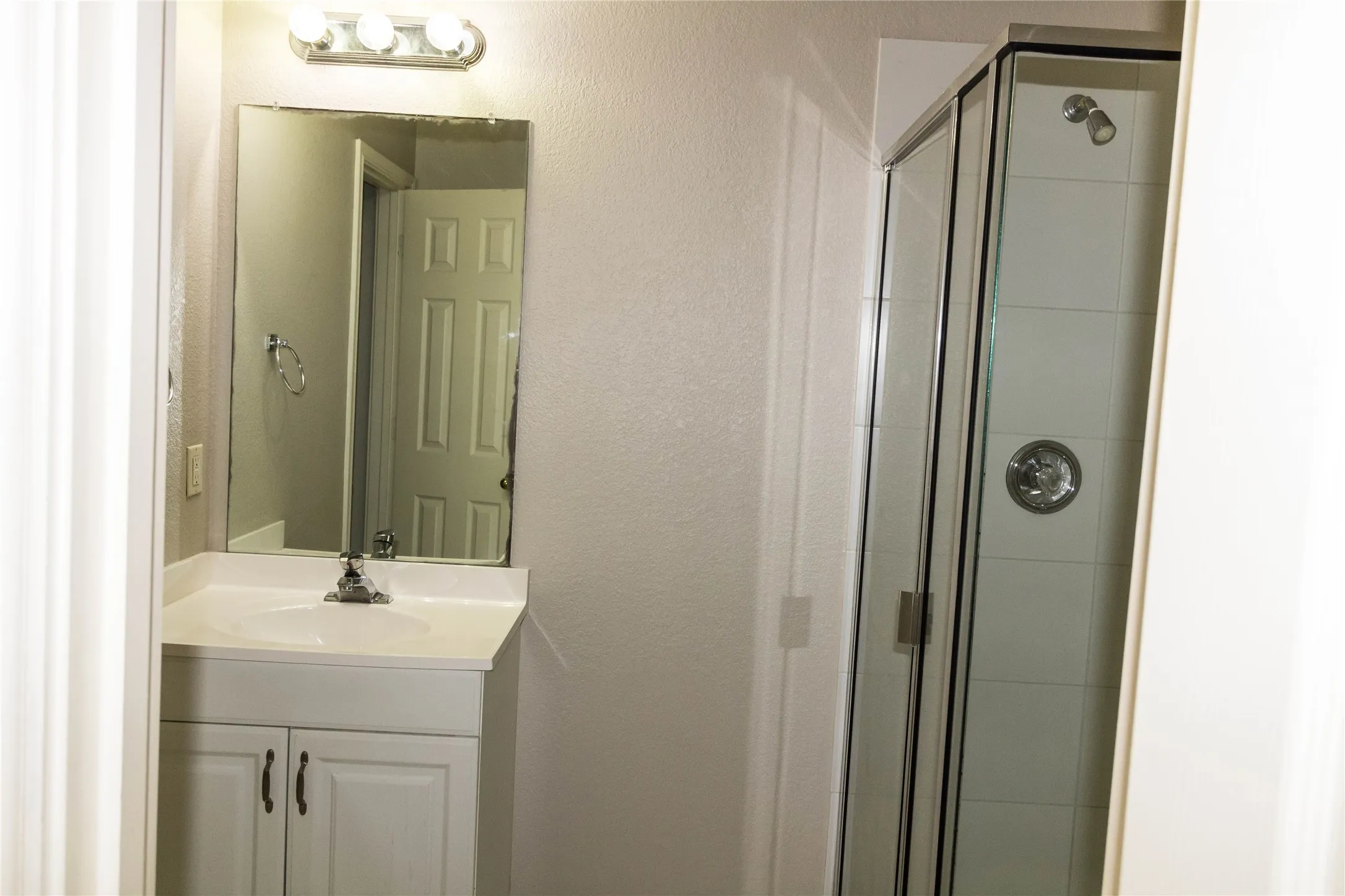 White vanity with integrated sink, chrome faucet, and mirrored cabinet