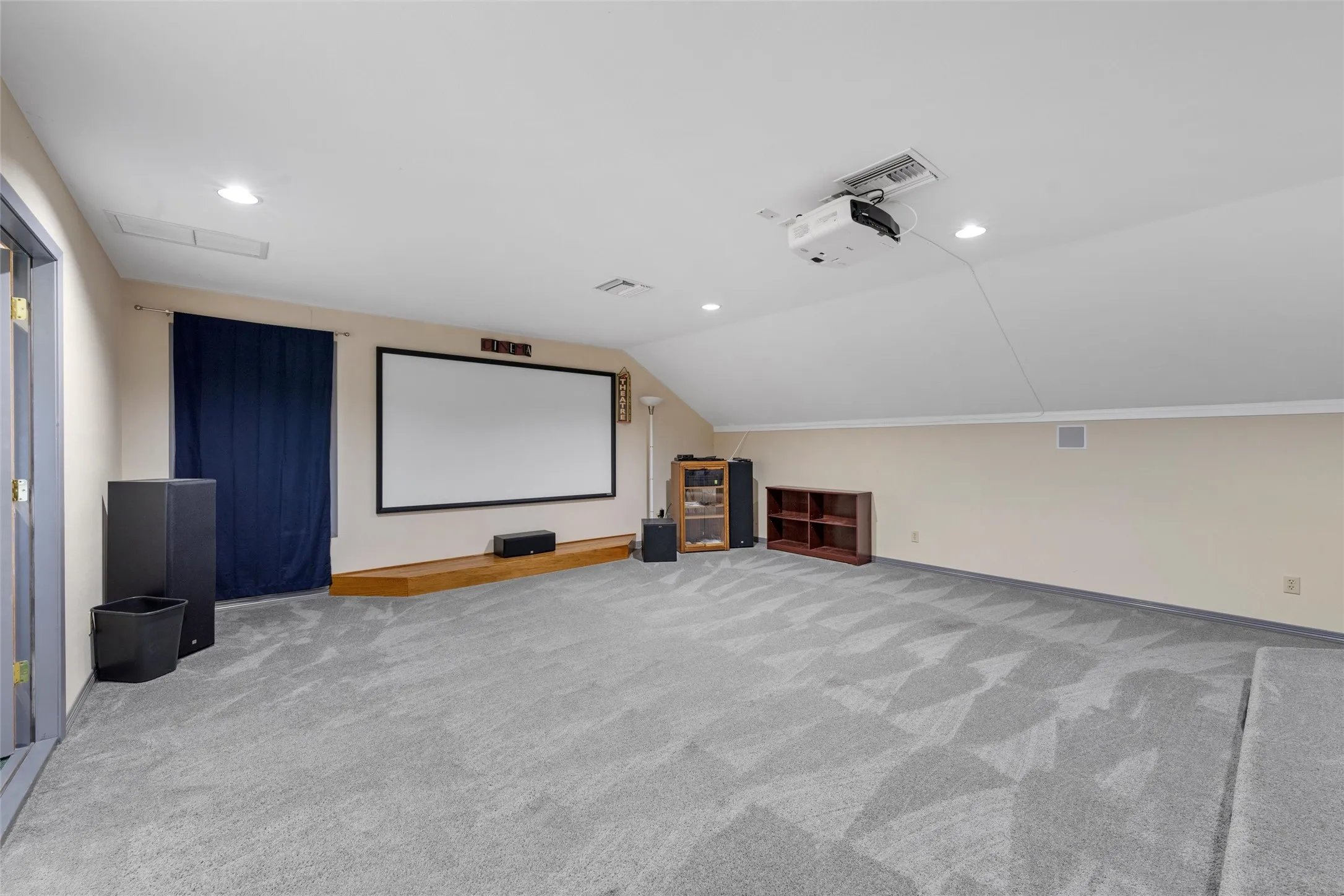 Spacious room featuring sloped ceilings, recessed lighting, and patterned carpeting
