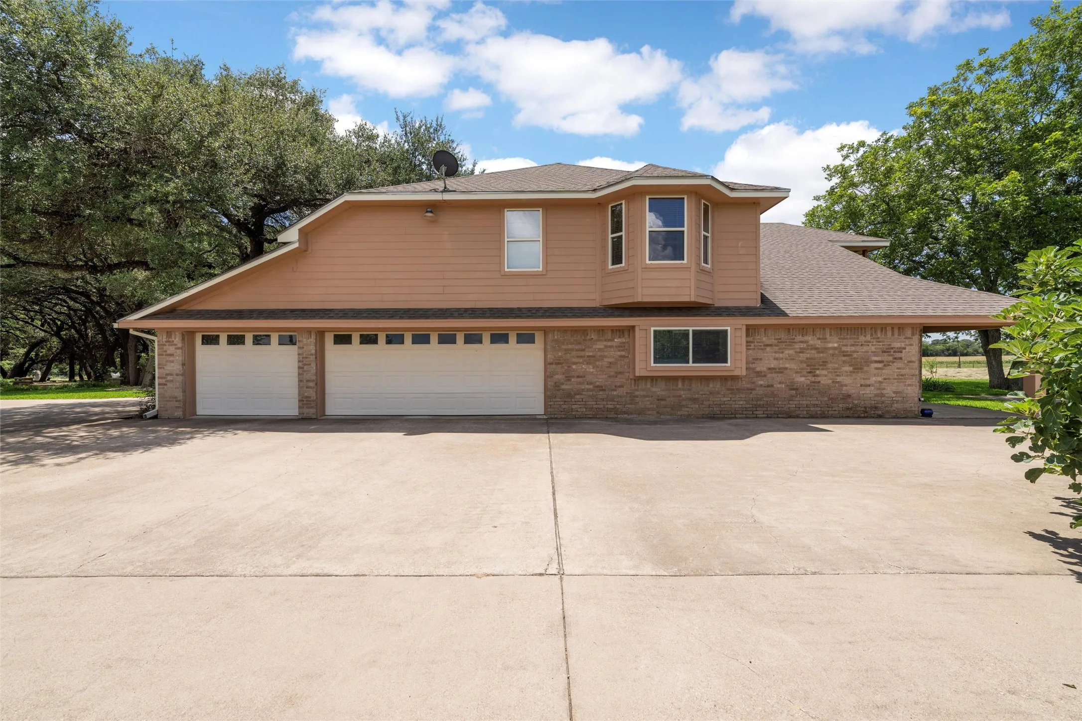 Two-story facade with a multi-car garage, brick and siding exterior, and a bay window feature