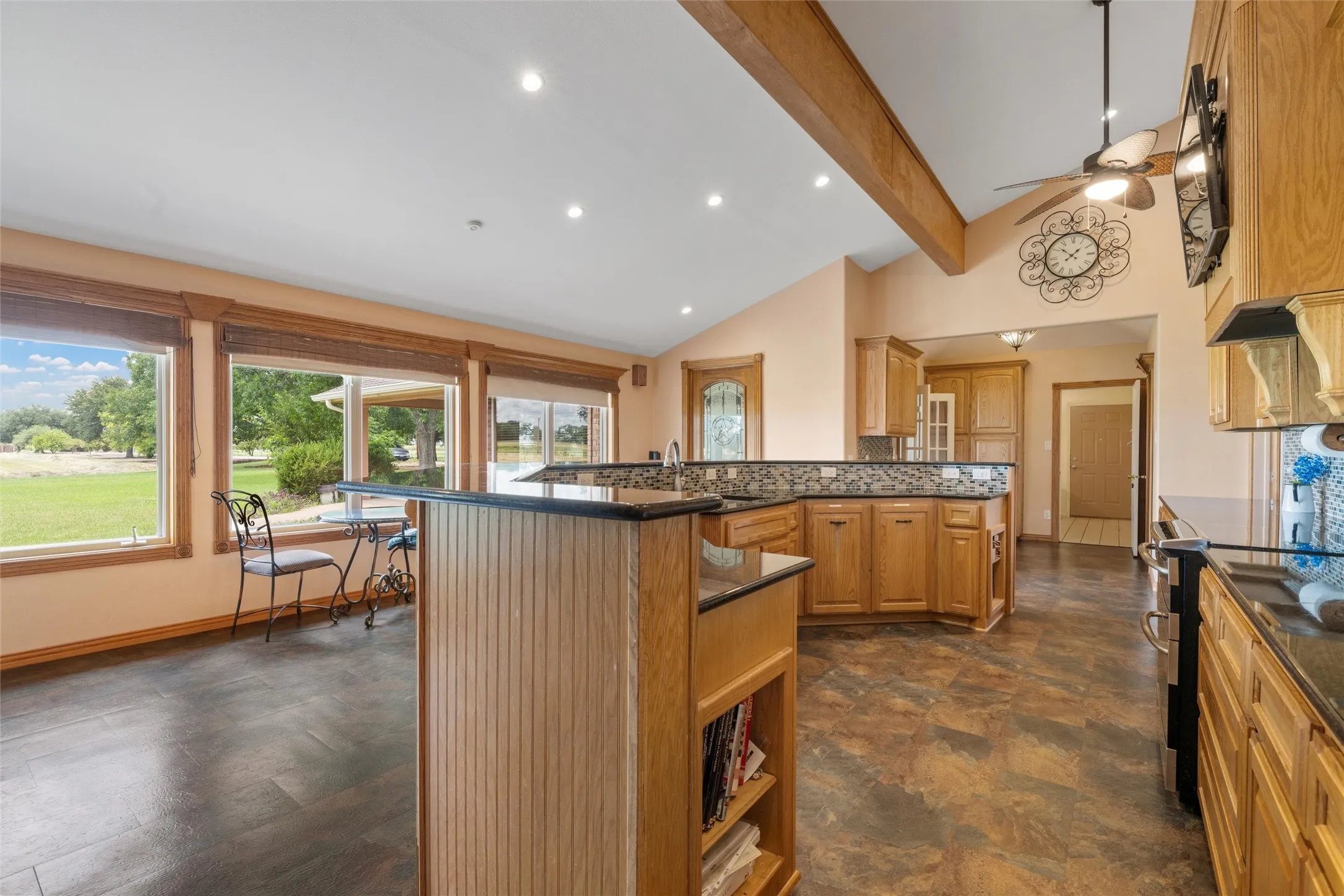 Kitchen area with wood-finish flooring, wood cabinetry, dark countertops, and a ceiling fan
