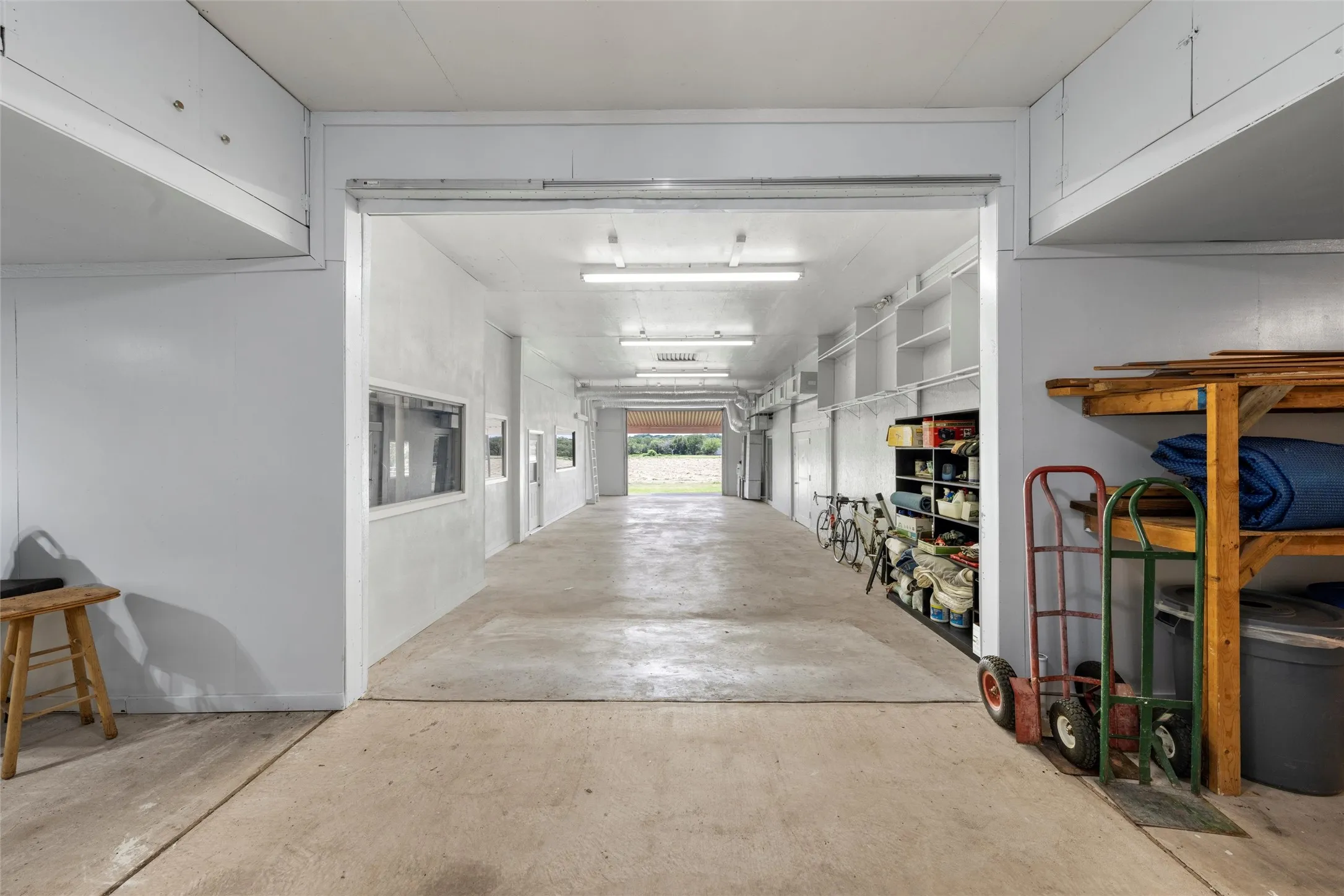 Spacious utility area with concrete flooring, overhead fluorescent lighting, and built-in shelving