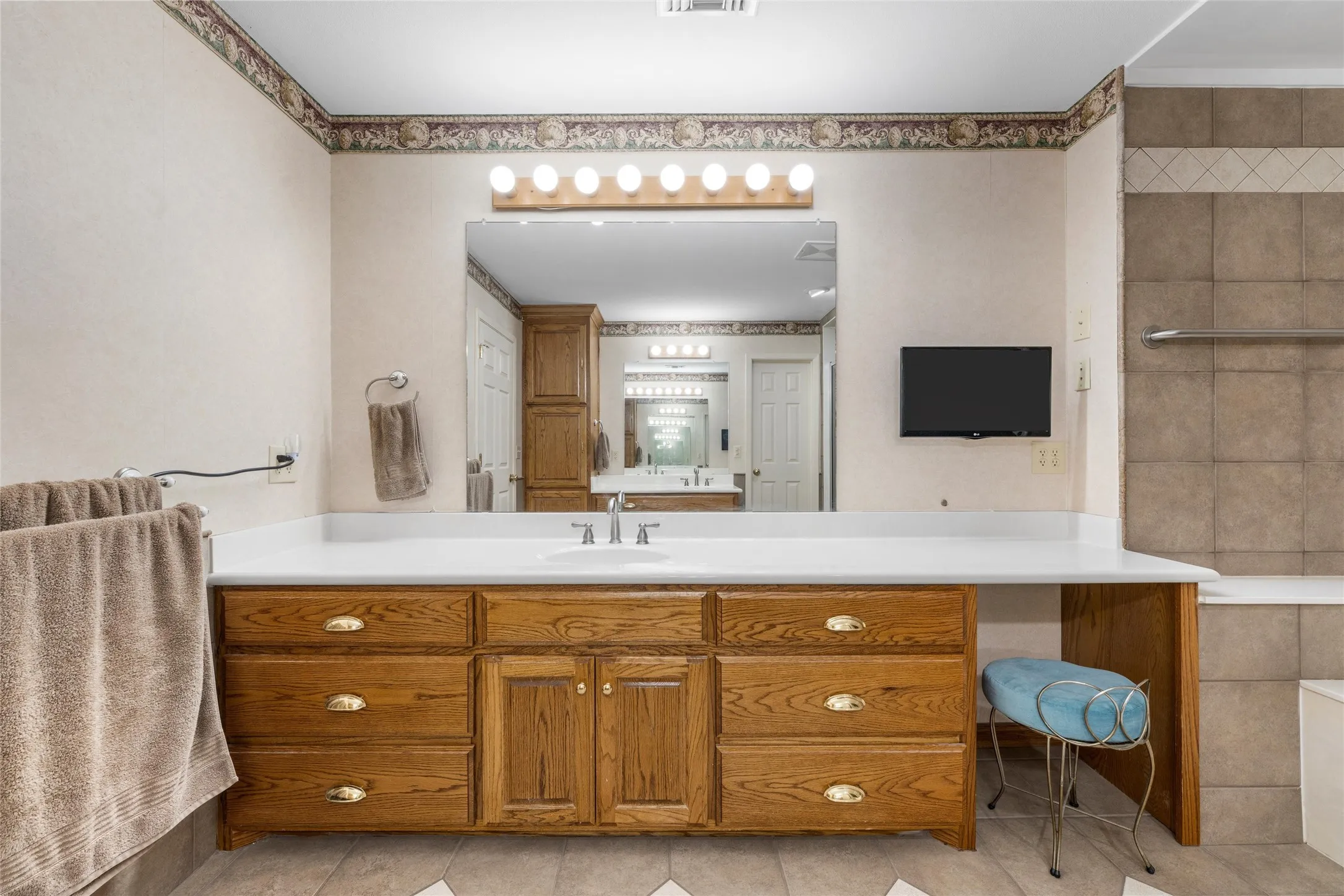 Wood-finish vanity with multiple drawers, white countertop, and integrated sink