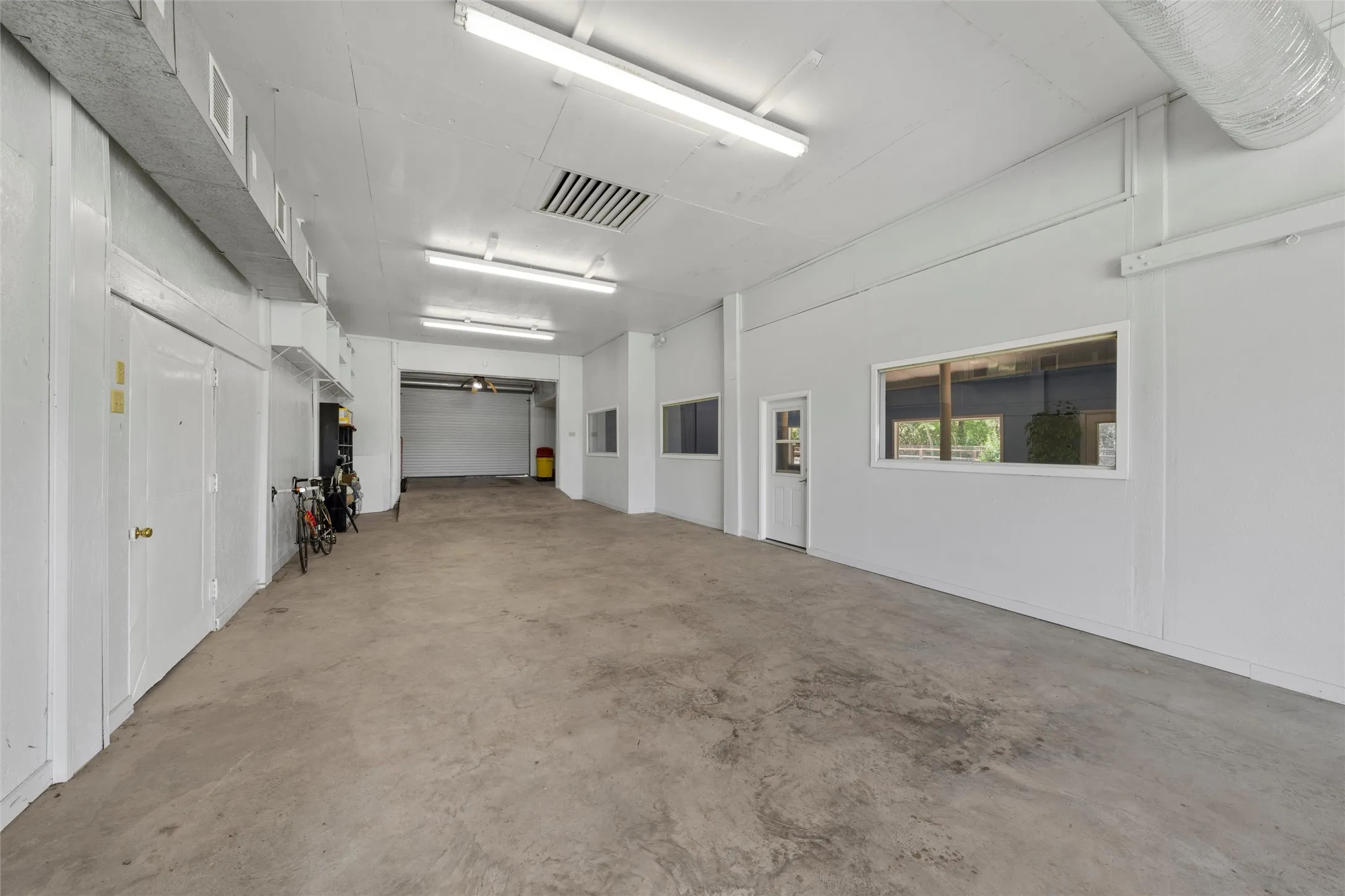 Concrete flooring, fluorescent lighting, internal windows, internal door, and a roll-up door