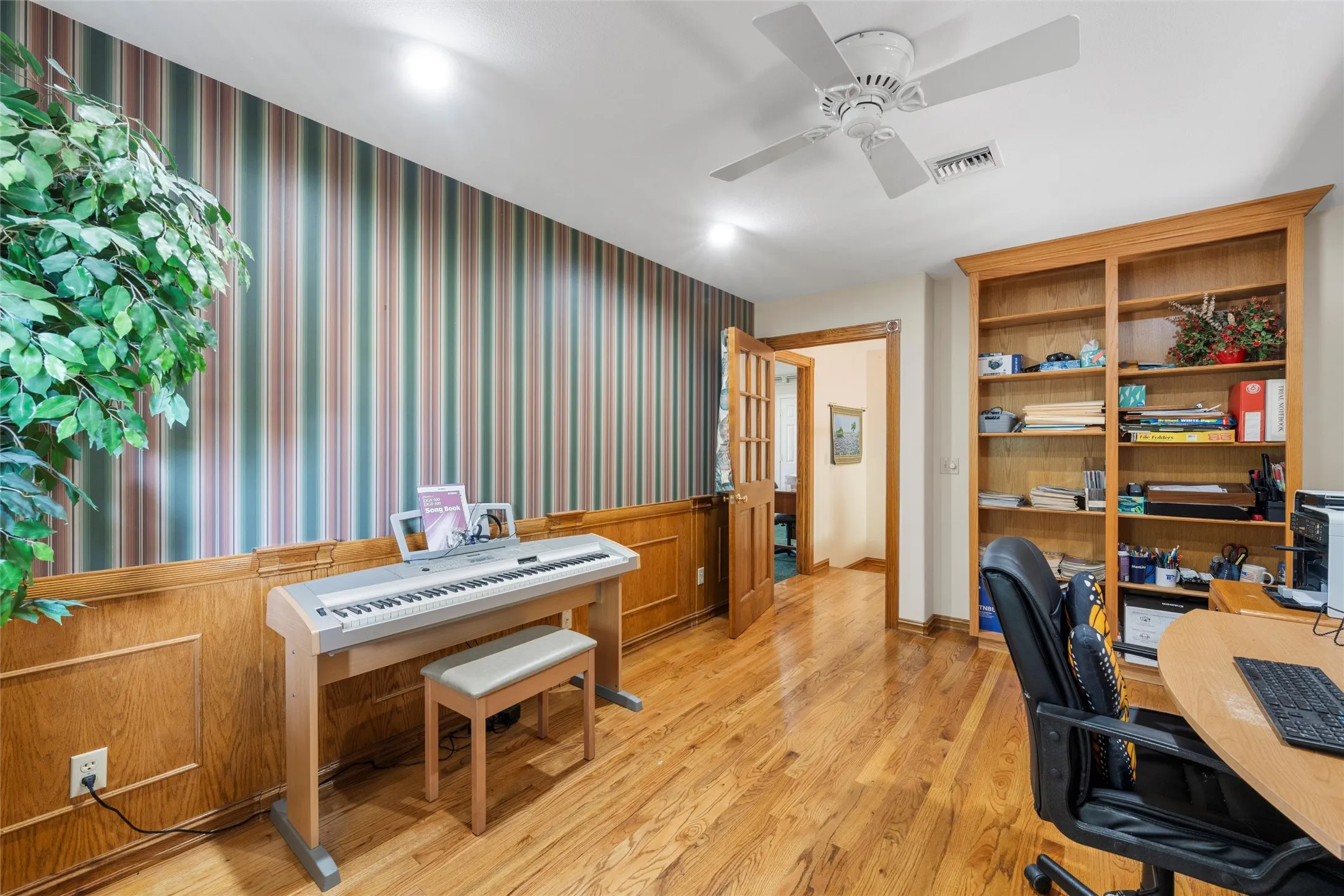 Hardwood flooring throughout, built-in shelving, wainscoting, ceiling fan, and recessed lighting