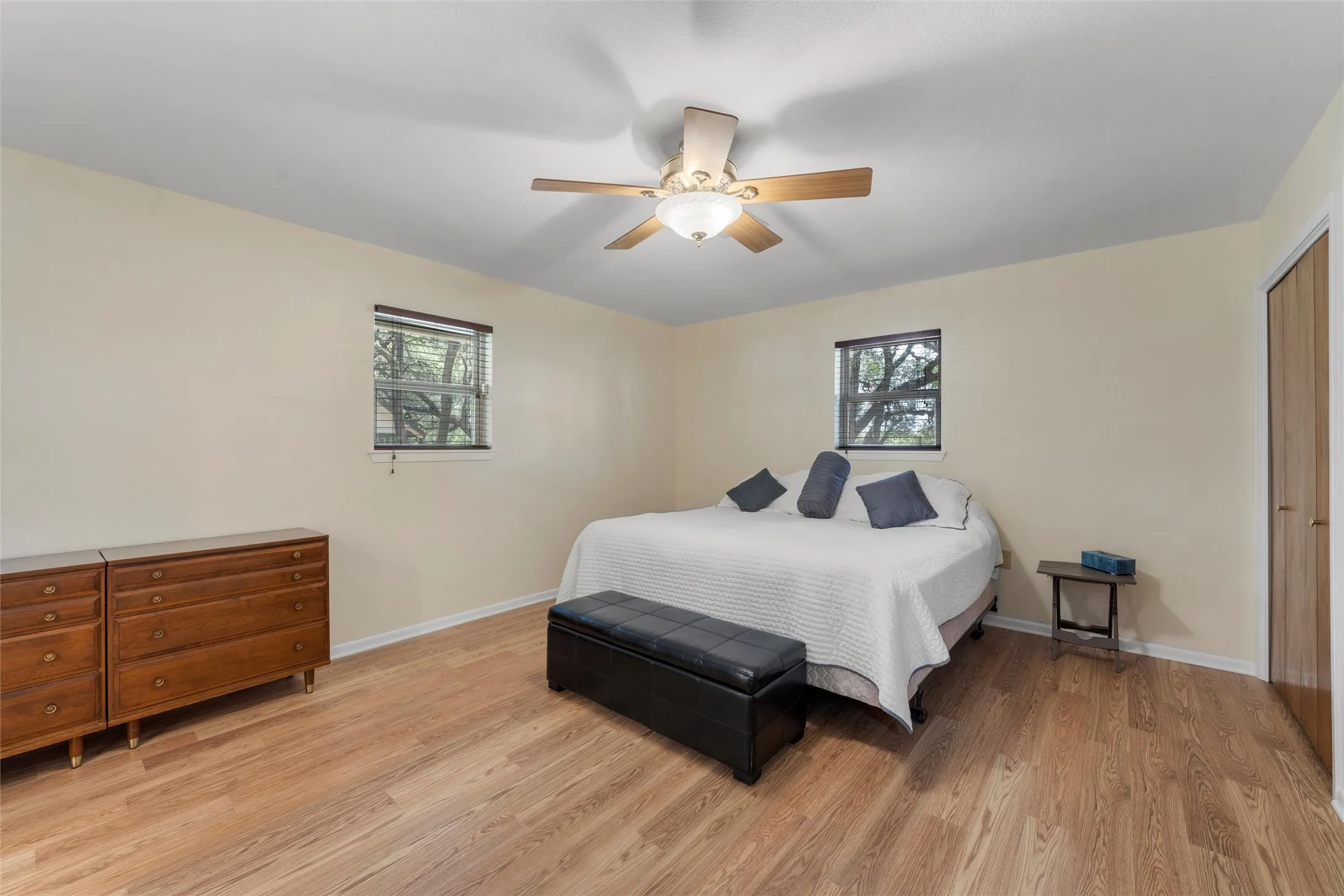 Wood-finish flooring, ceiling fan, and two windows with blinds