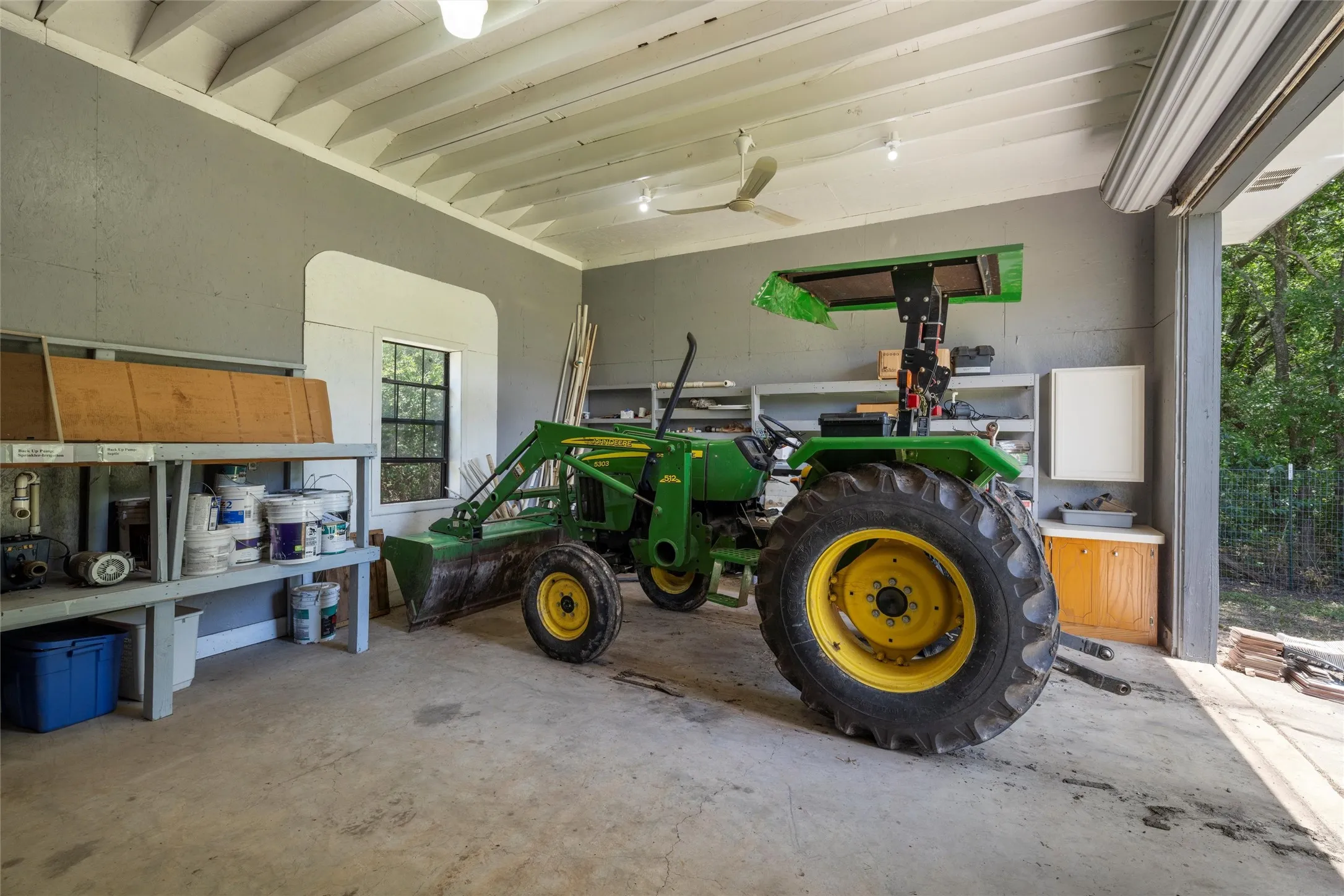 Concrete flooring garage with an exposed beam ceiling, recessed lighting, and a roll-up garage door