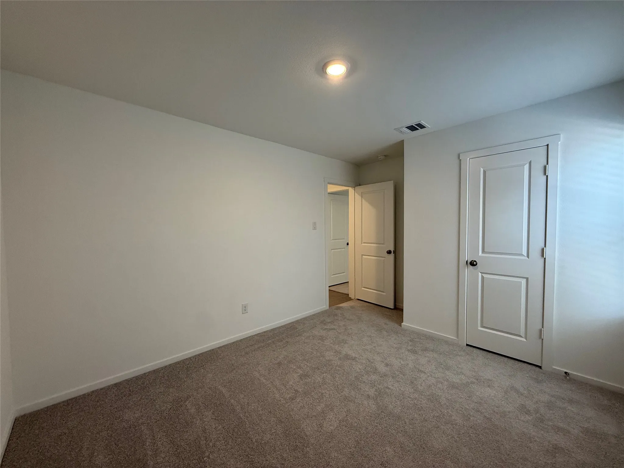 Recessed ceiling lighting, neutral carpet flooring, white interior doors, and crisp white wall paint