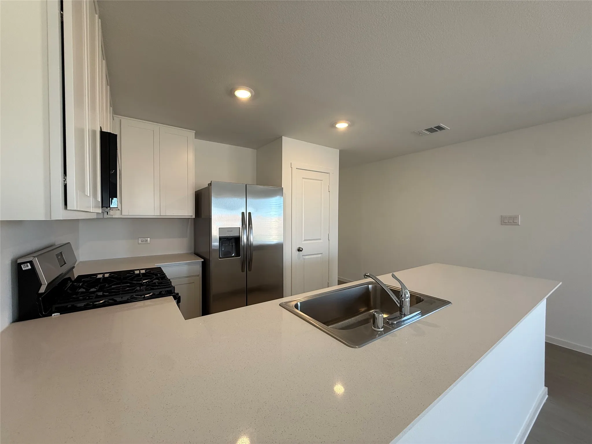 Kitchen featuring white cabinetry, stainless steel appliances, recessed lighting, and an island with an undermount sink