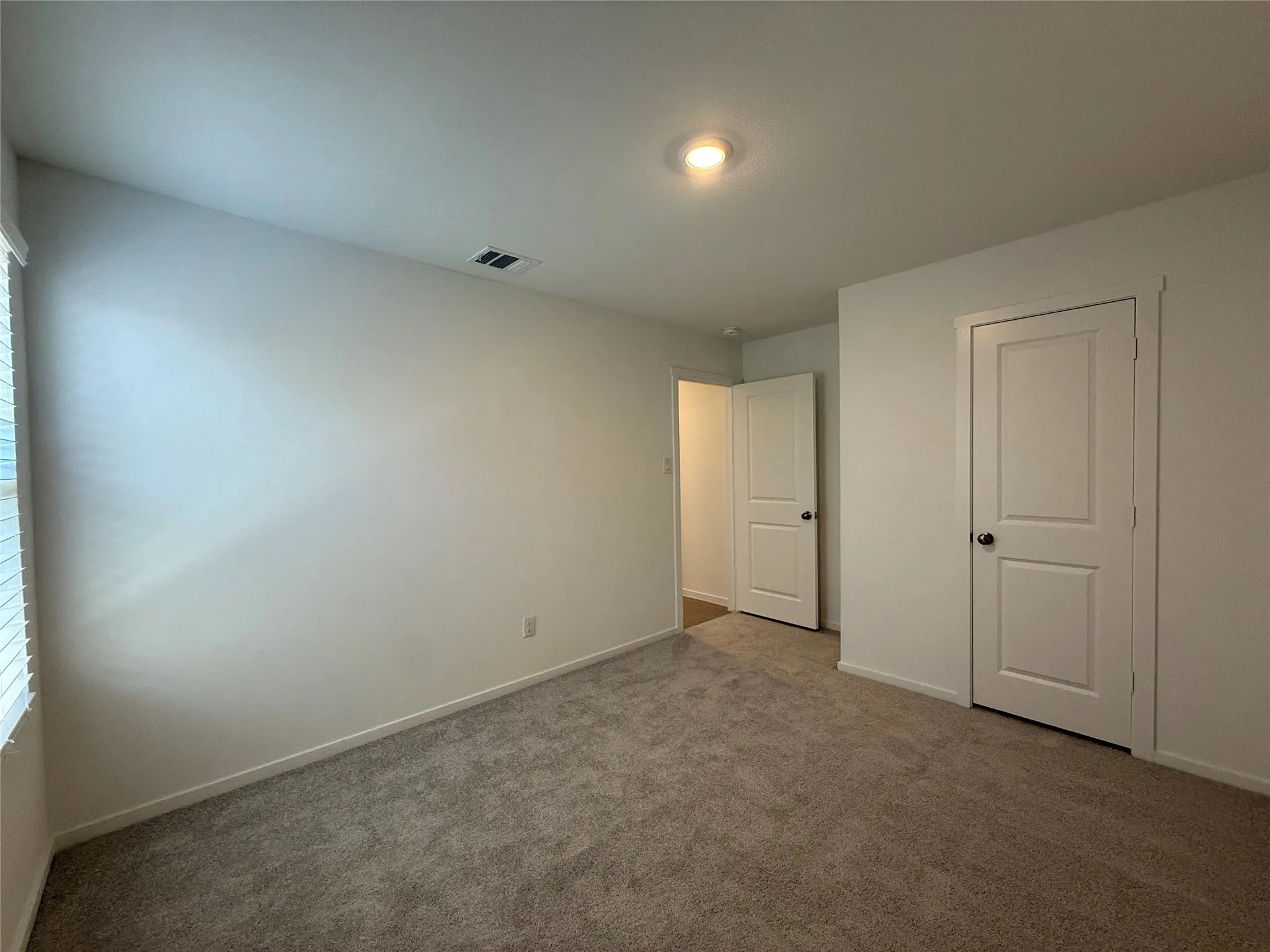 Neutral tone wall paint, recessed ceiling light, carpet flooring, and white two-panel doors
