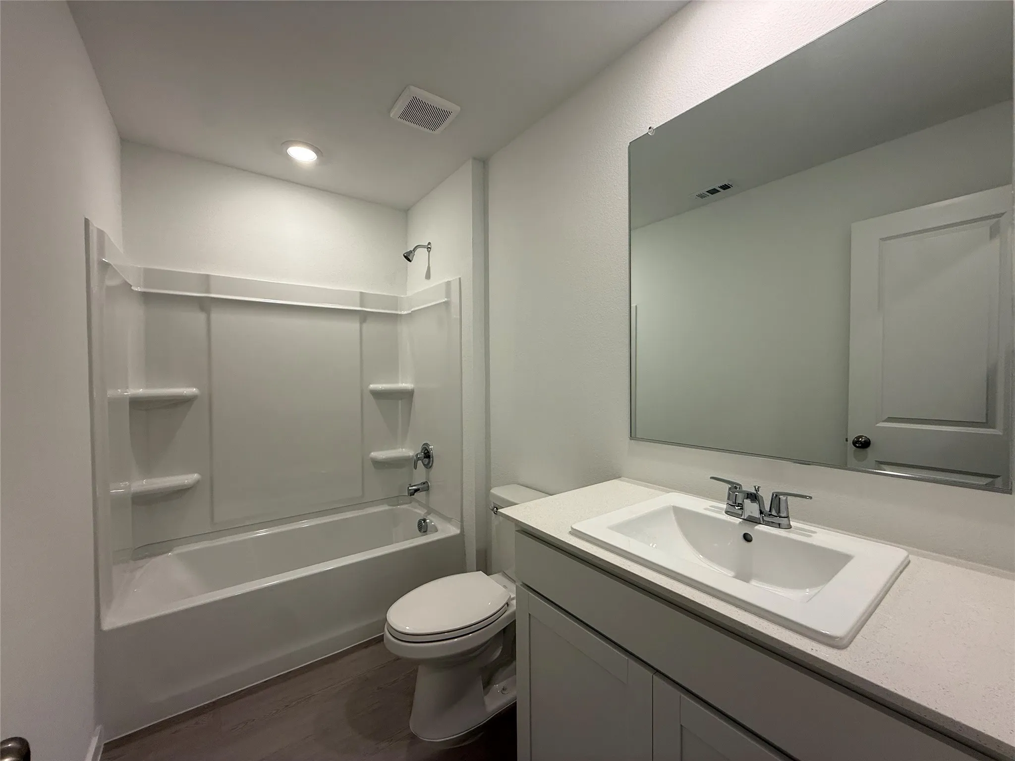 White vanity with an integrated rectangular sink, chrome fixtures, and a large wall-mounted mirror