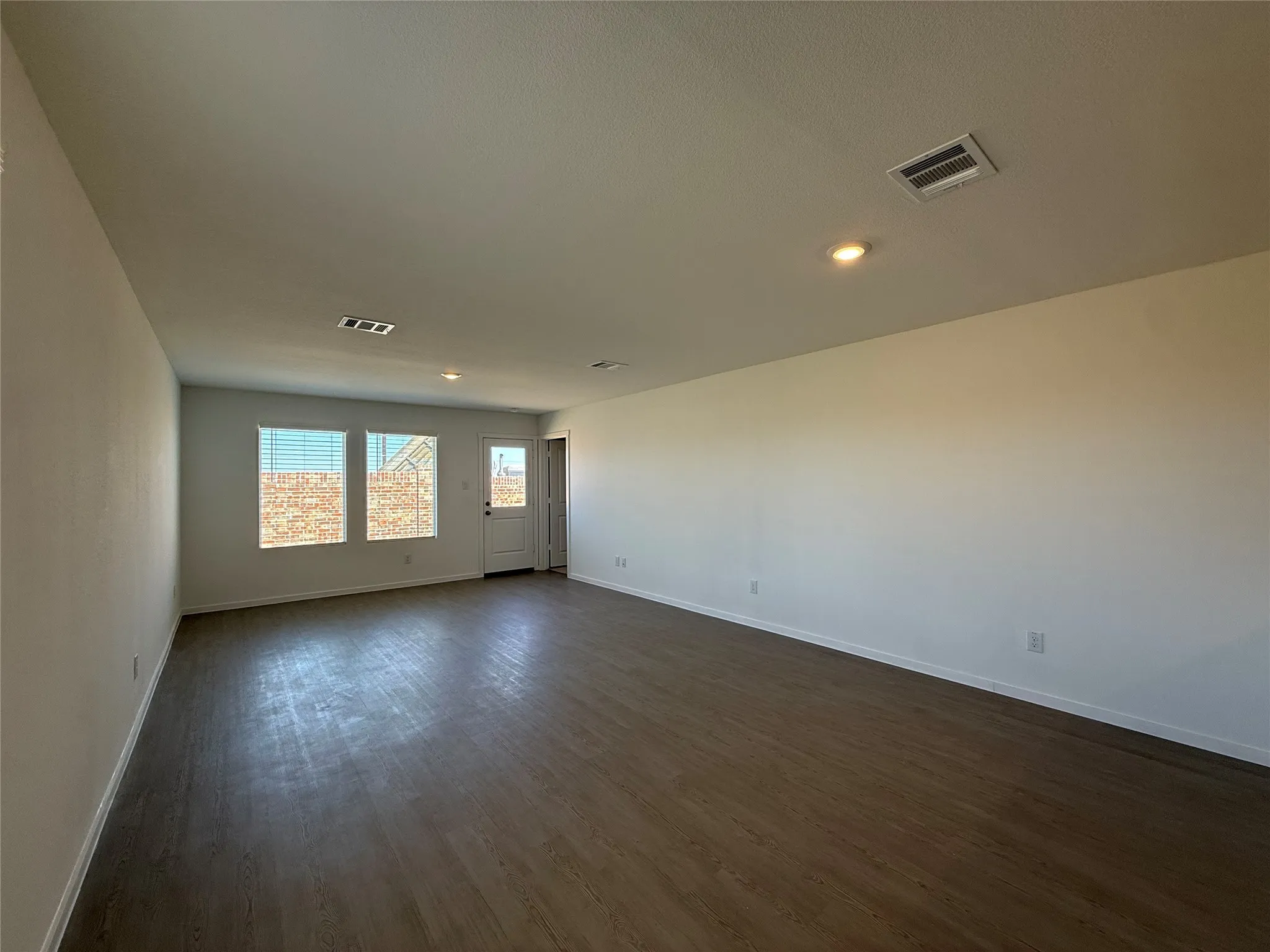 Wood-finish flooring, recessed lighting, and multiple windows with horizontal blinds
