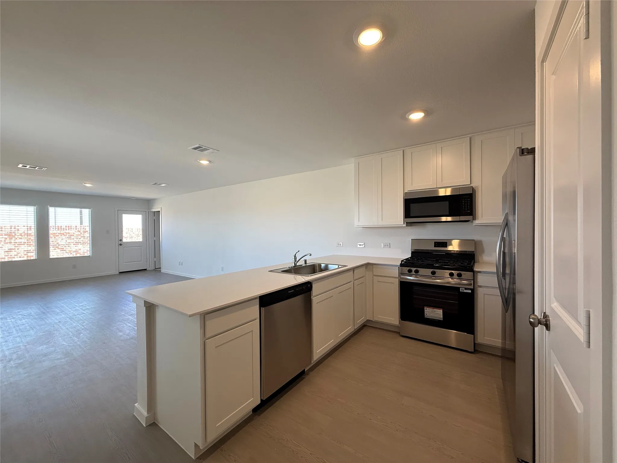 Kitchen featuring white shaker cabinetry, stainless steel appliances, a gas range, and wood-finish flooring