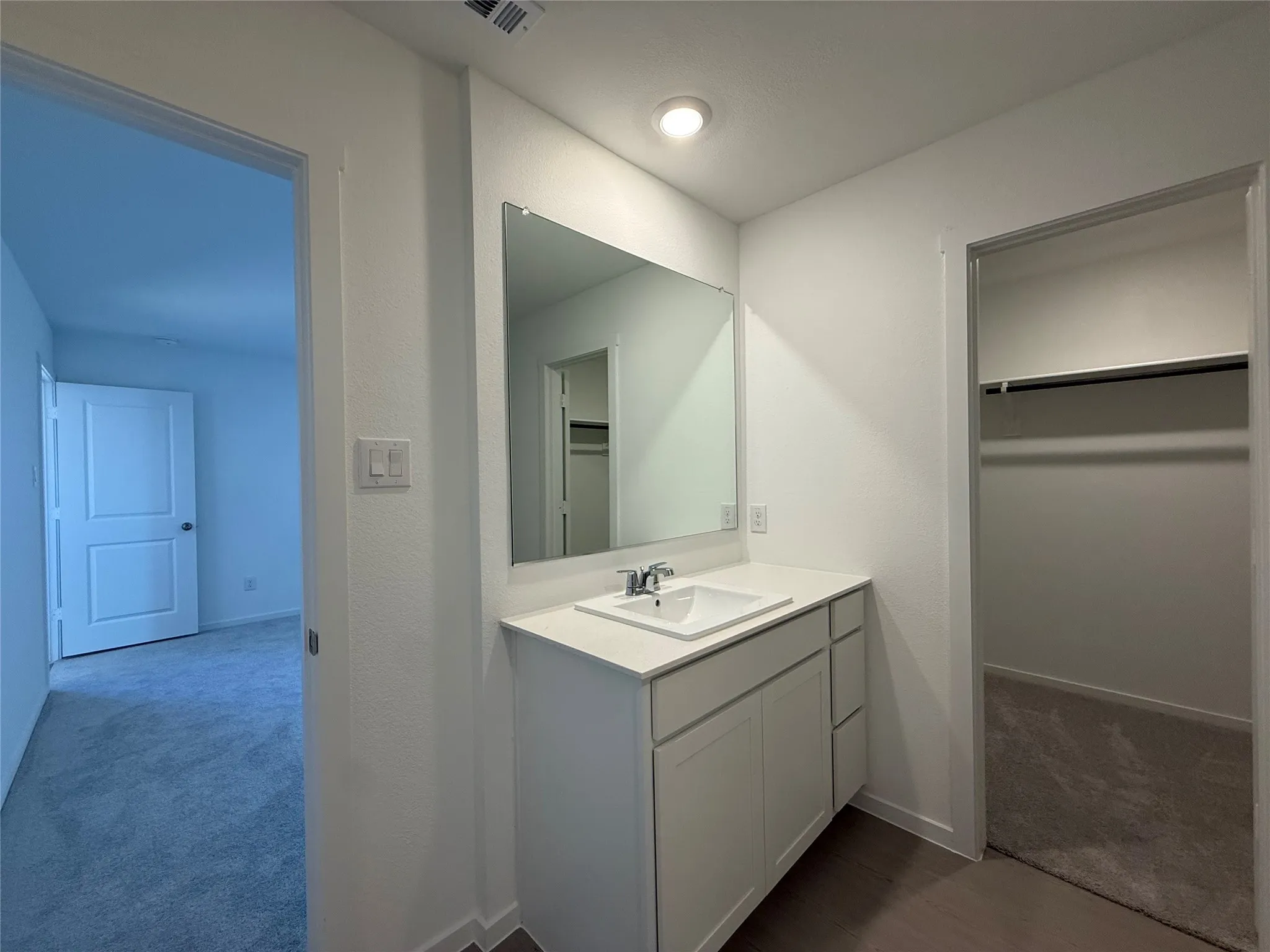 Vanity with an integrated rectangular sink, chrome faucet, and under-cabinet storage